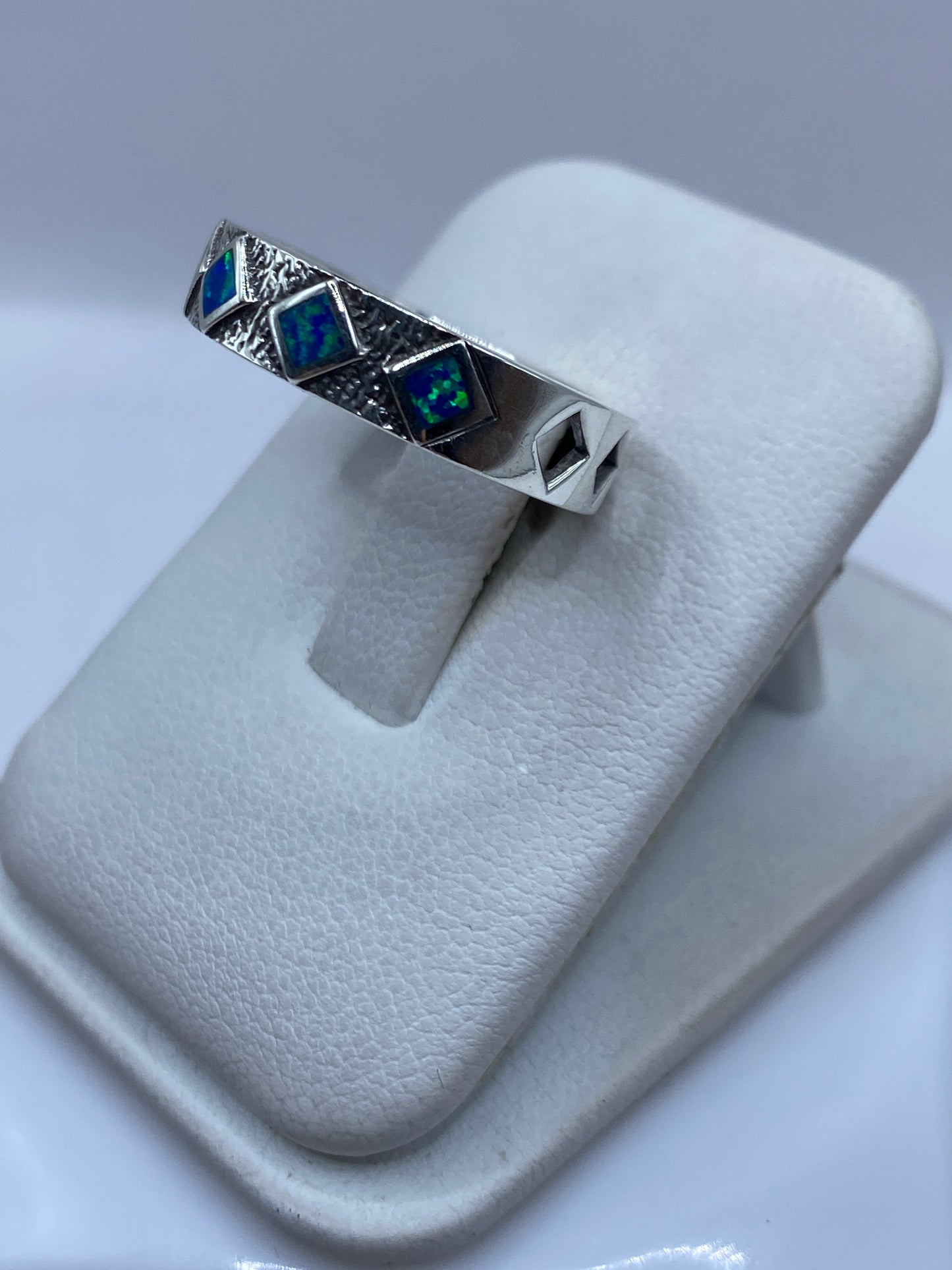 Detalle lateral del anillo mostrando el juego de colores azul y verde del ópalo