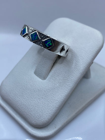 Detalle lateral del anillo mostrando el juego de colores azul y verde del ópalo