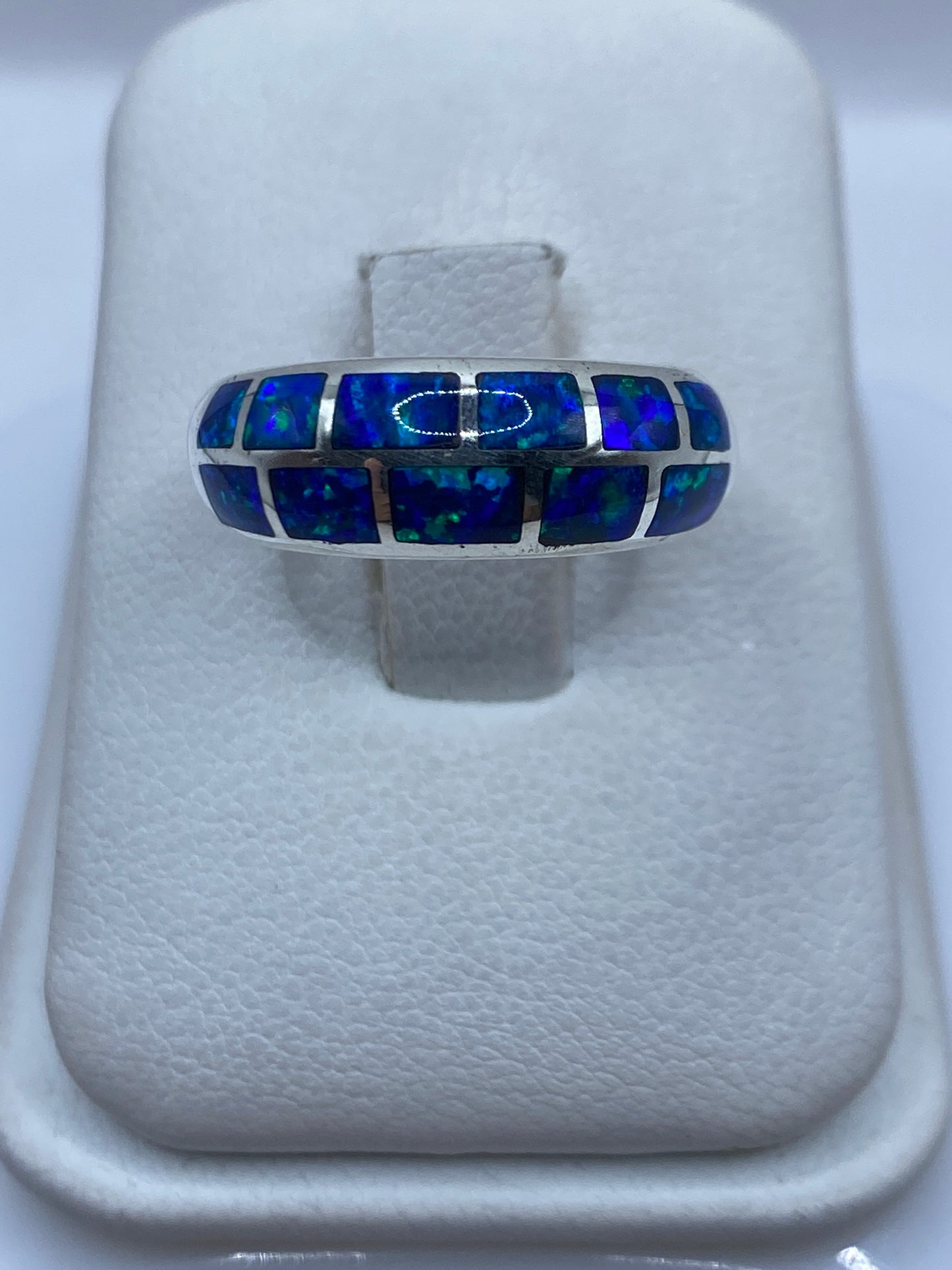 Anillo de plata .950 con ópalo de fuego azul en la mano, mostrando el brillo y fuego natural de la piedra
