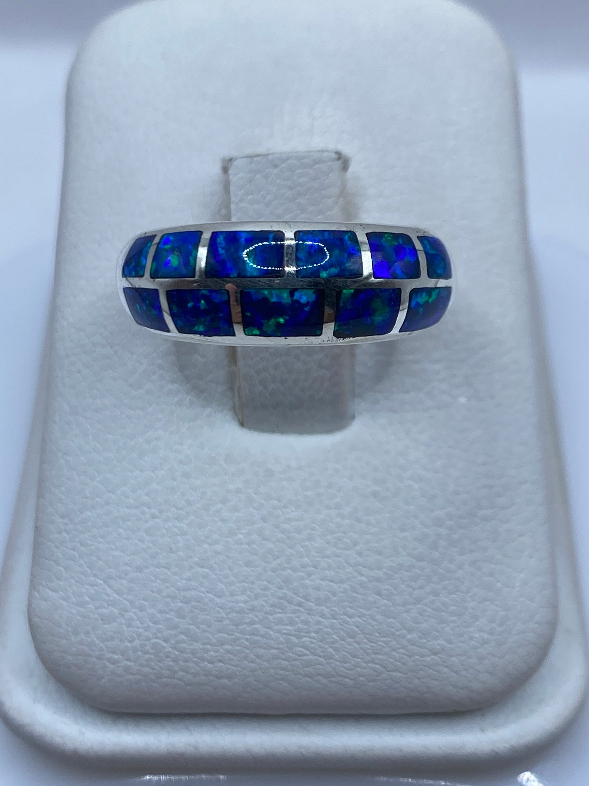 Anillo de plata .950 con ópalo de fuego azul en la mano, mostrando el brillo y fuego natural de la piedra