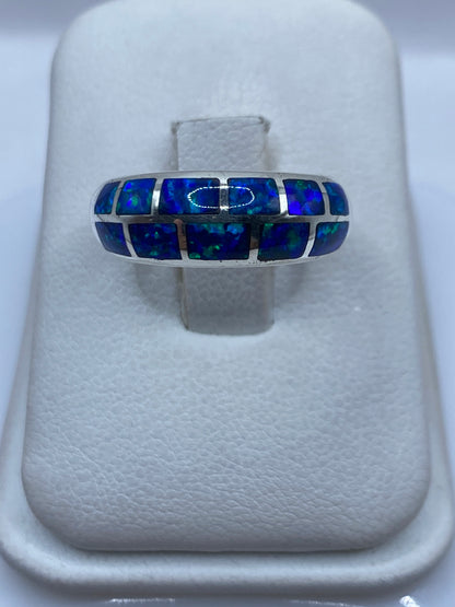 Anillo de plata .950 con ópalo de fuego azul en la mano, mostrando el brillo y fuego natural de la piedra