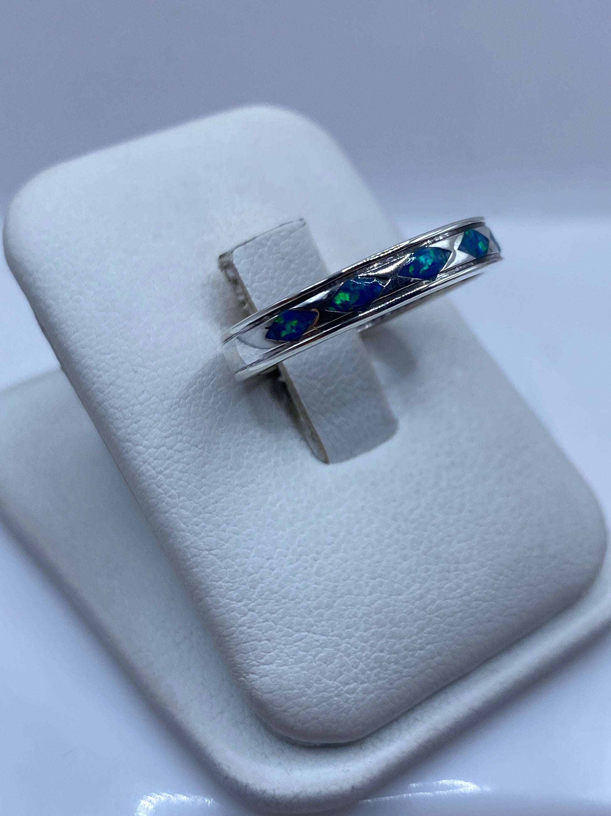 Anillo unisex con ópalo de fuego sobre dedo mostrando los destellos azules naturales