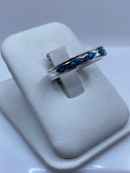 Anillo unisex con ópalo de fuego sobre dedo mostrando los destellos azules naturales