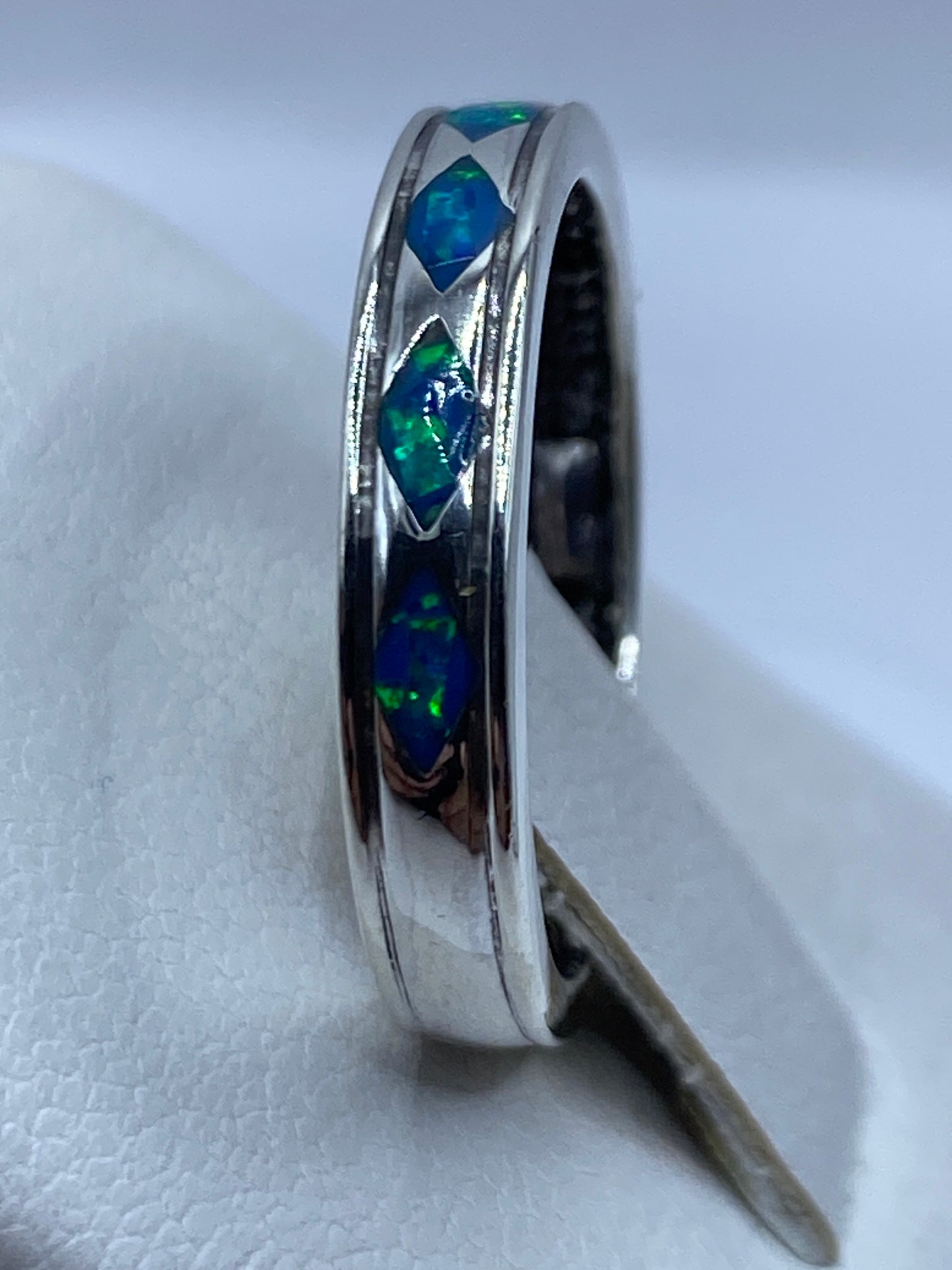 Detalle lateral del anillo de plata .950 con fuego azul del ópalo visible
