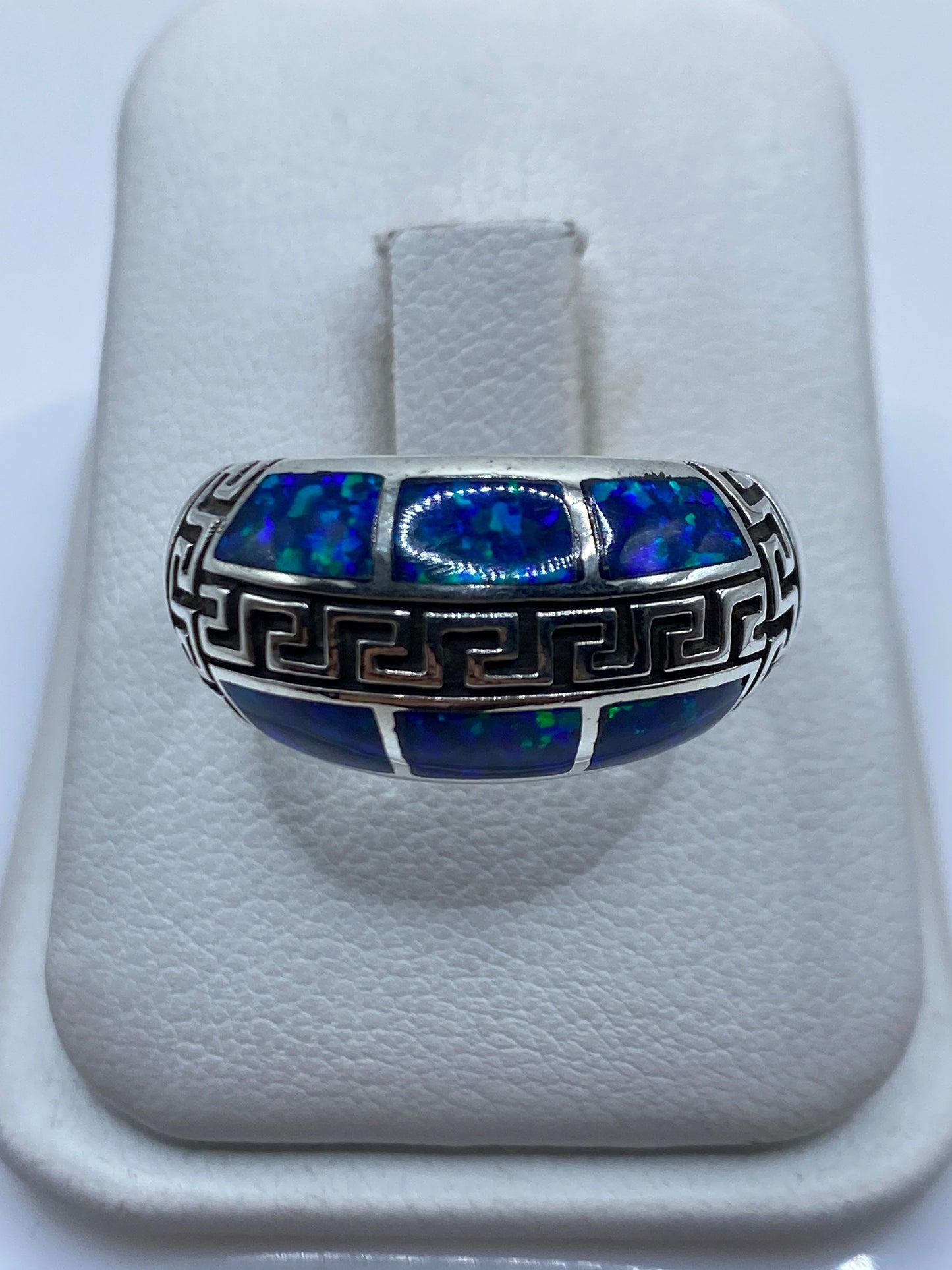 Anillo de plata .950 con ópalo de fuego azul y grecas étnicas talladas en la mano de una persona