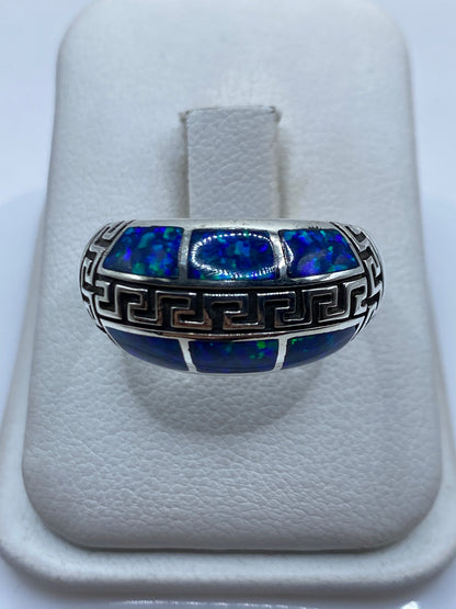 Anillo de plata .950 con ópalo de fuego azul y grecas étnicas talladas en la mano de una persona