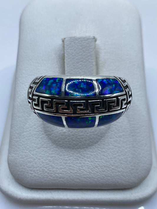 Anillo de plata .950 con ópalo de fuego azul y grecas étnicas talladas en la mano de una persona
