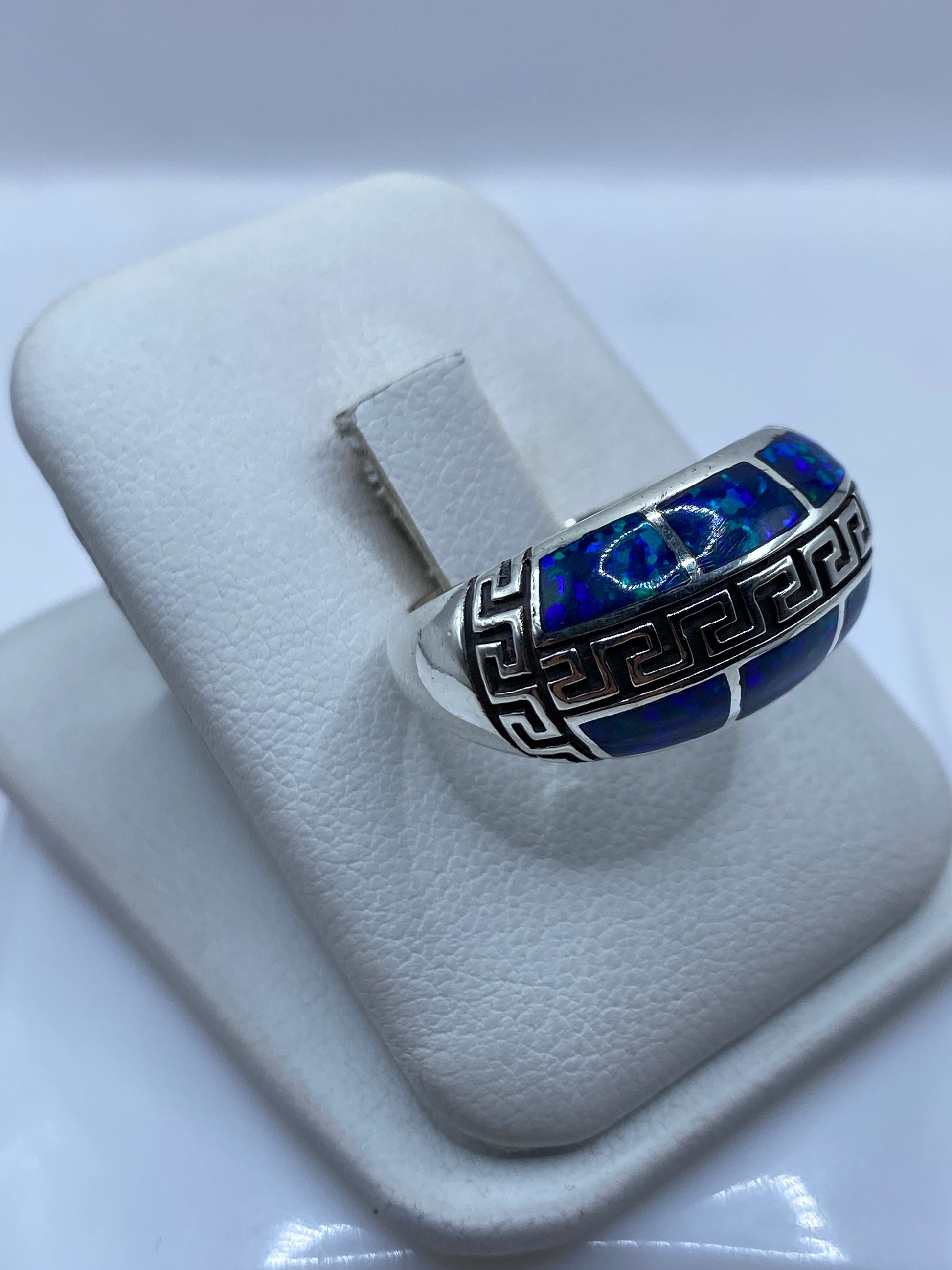 Vista frontal del anillo étnico mostrando el juego de luces azul y verde del ópalo de fuego