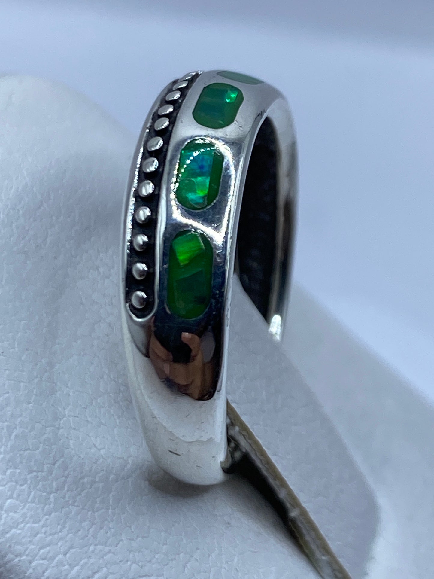 Detalle cercano del engaste del ópalo de fuego en plata .950, con acabado artesanal