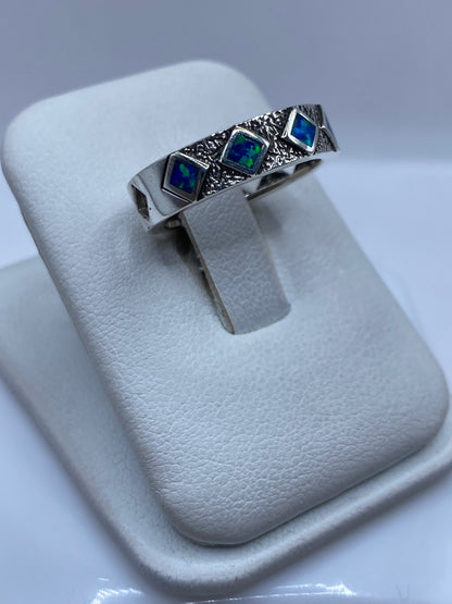 Detalle del ópalo de fuego azul mostrando juego de colores verdes y turquesas en el anillo