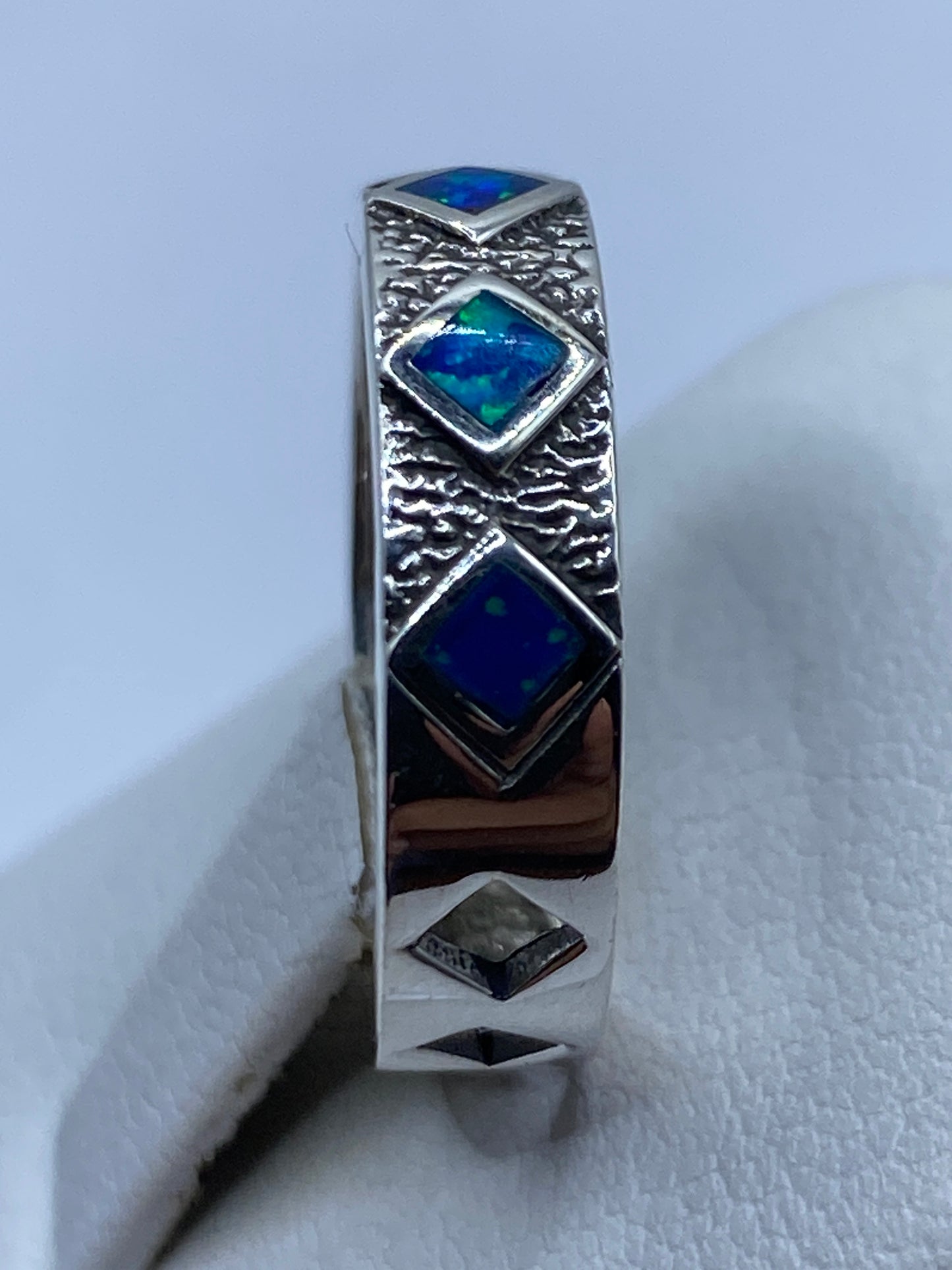 Anillo de plata pura .950 en la mano, ópalo de fuego azul brillando bajo luz natural