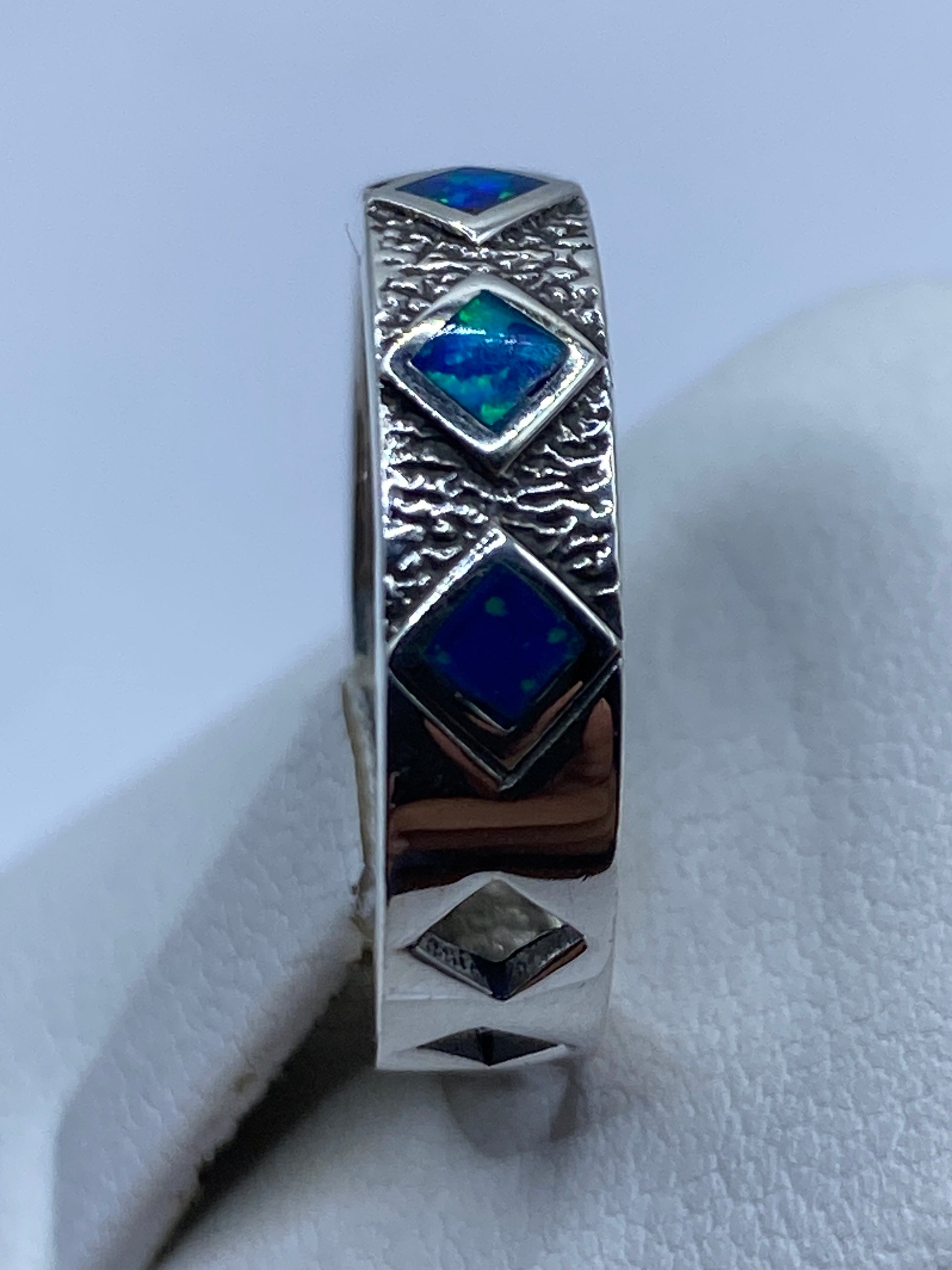 Anillo de plata pura .950 en la mano, ópalo de fuego azul brillando bajo luz natural