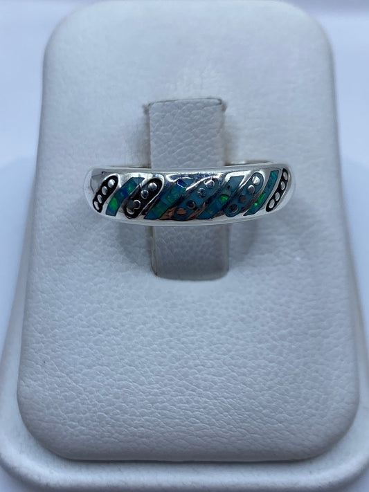 Anillo de plata .950 con ópalo de fuego azul engastado, visto de frente sobre almohada blanca