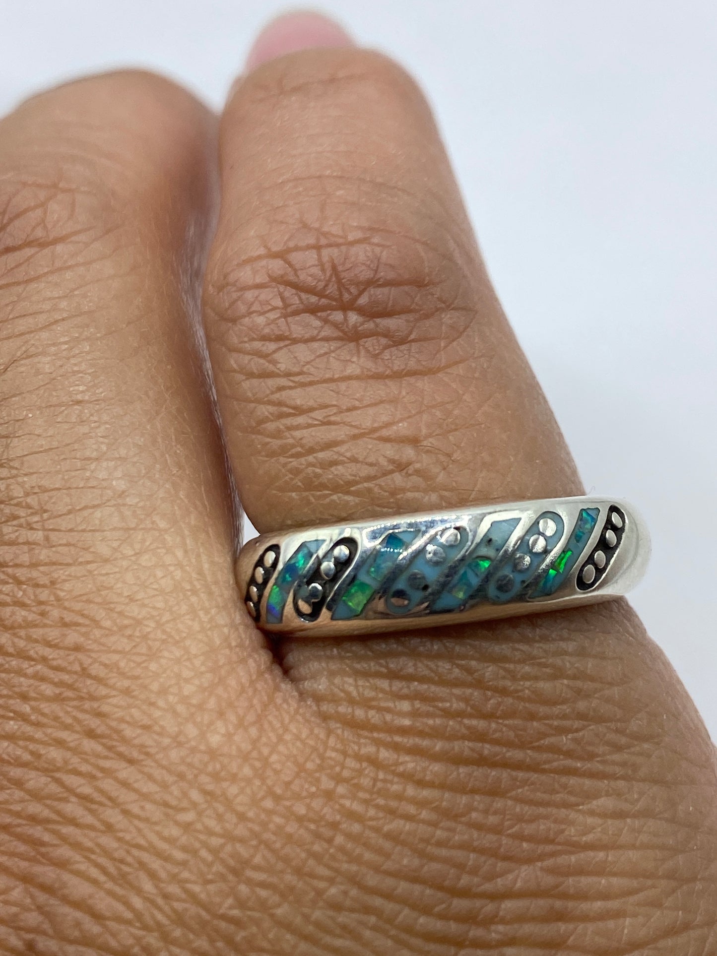 Anillo en dedo mostrando cómo el ópalo cambia de color según el movimiento, con sello 950 visible en el interior