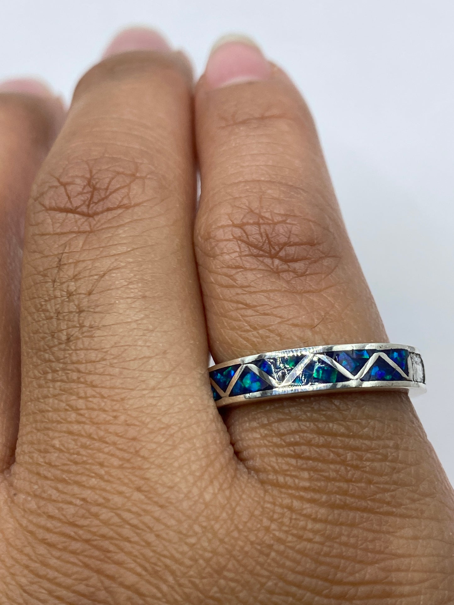 Anillo de plata con ópalo azul puesto en dedo, mostrando comodidad y brillo natural