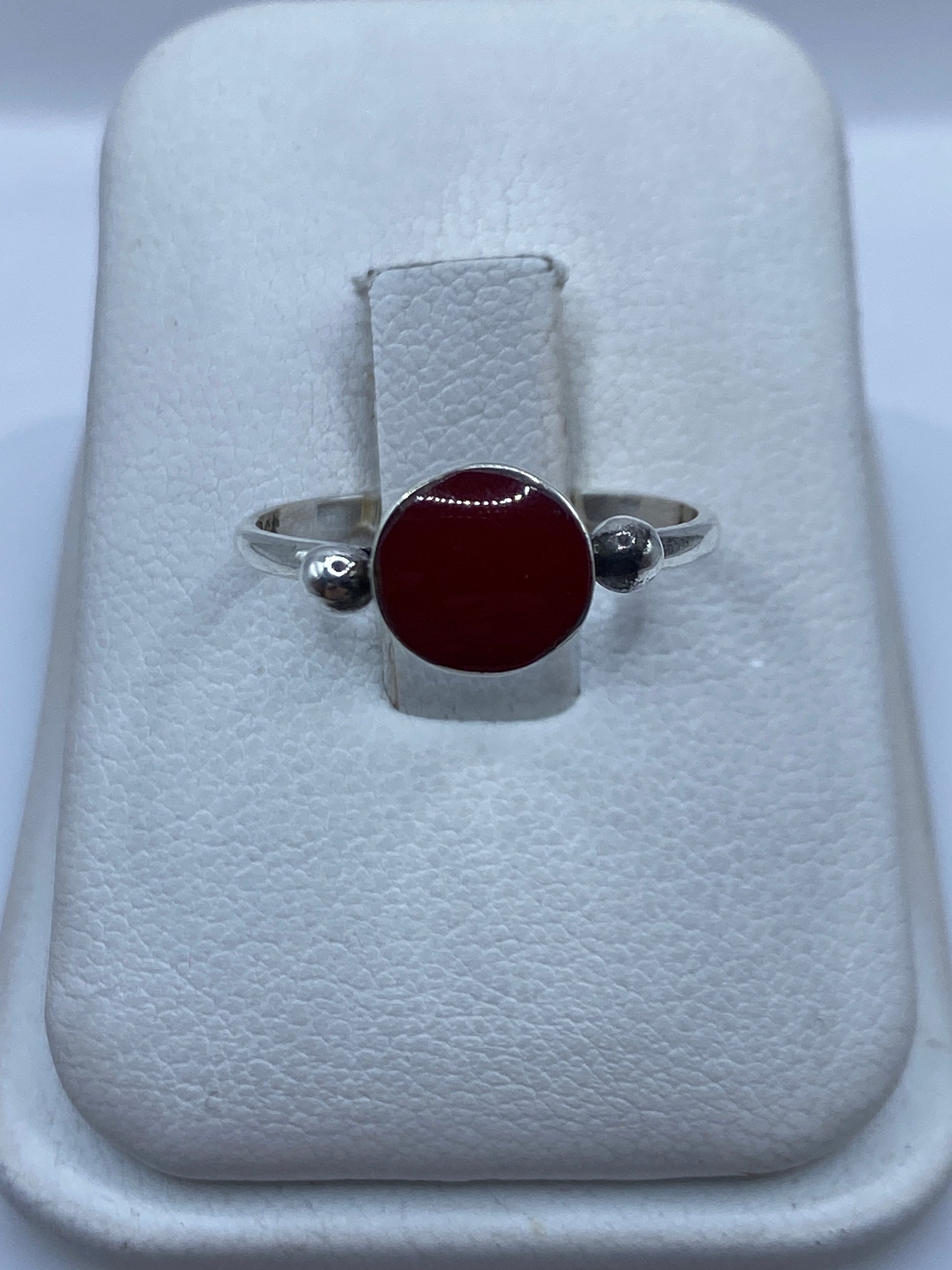 Anillo de plata .950 con piedra roja central en estuche blanco sobre fondo gris