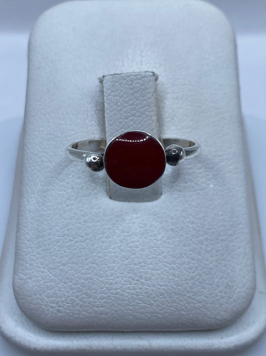 Anillo de plata .950 con piedra roja central en estuche blanco sobre fondo gris