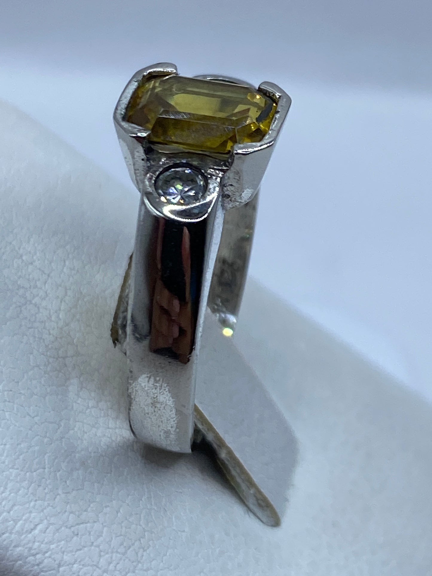 Anillo solitario puesto en la mano, circonia amarilla reflejando luz cálida