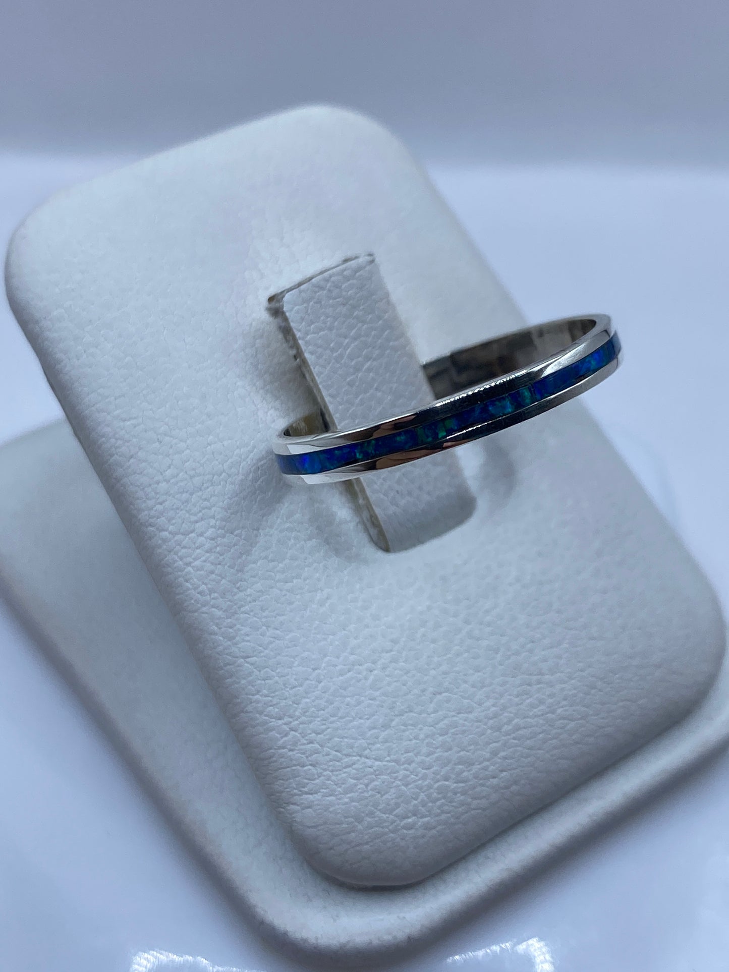 Ópalo de fuego azul mostrando juego de colores en anillo de plata minimalista