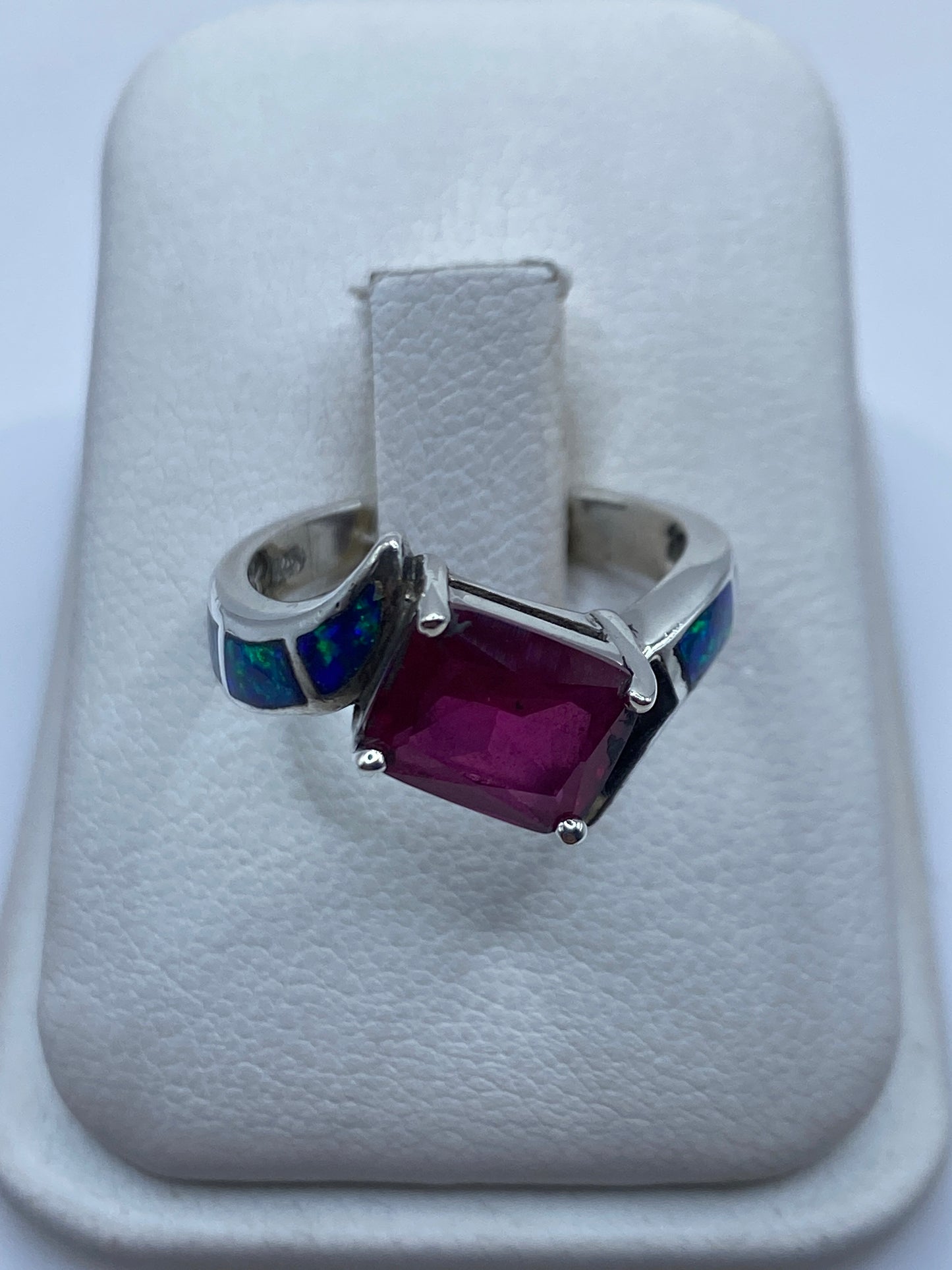 Anillo de plata artesanal con ópalo de fuego azul sobre cojín blanco