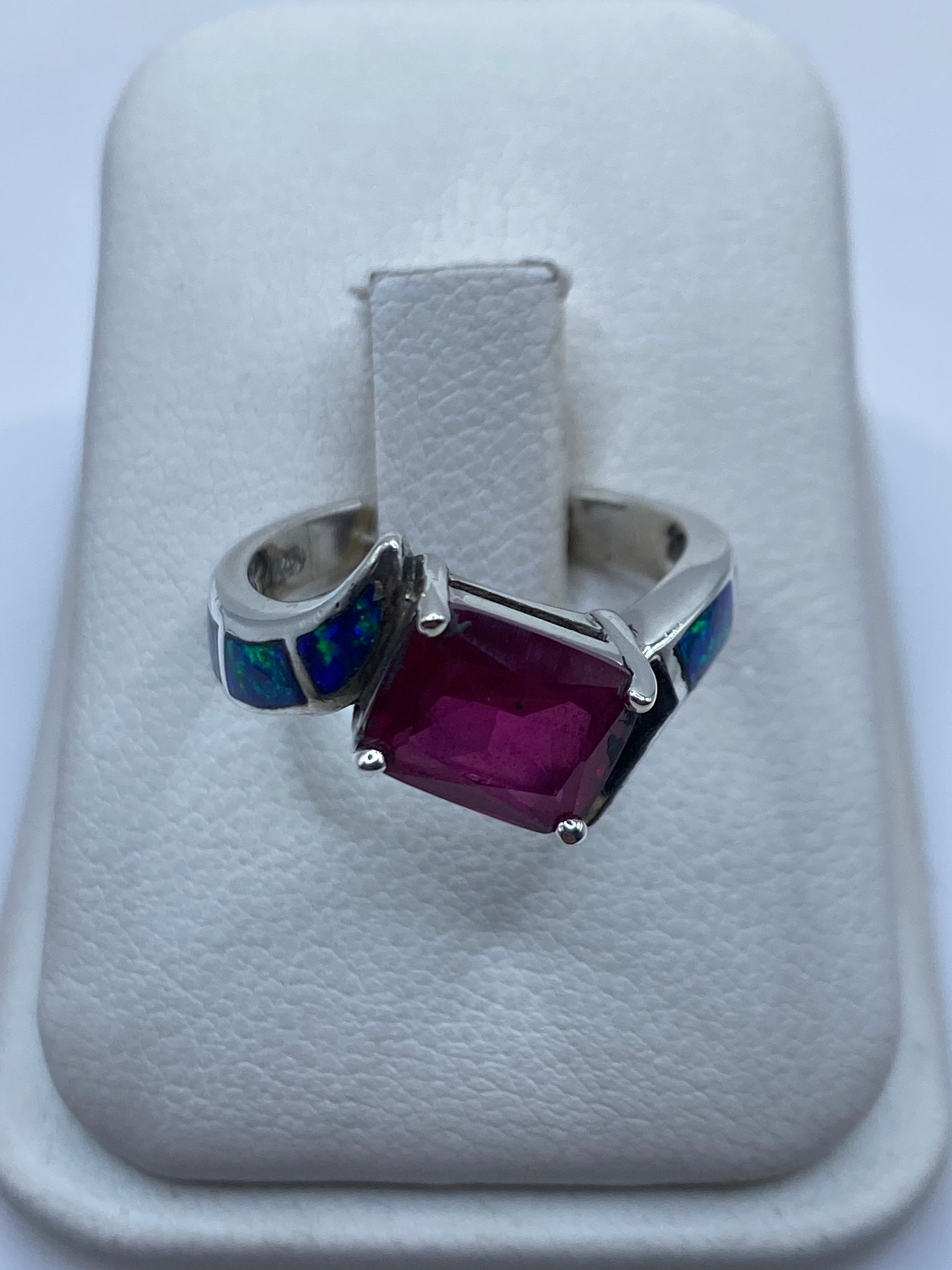 Anillo de plata artesanal con ópalo de fuego azul sobre cojín blanco