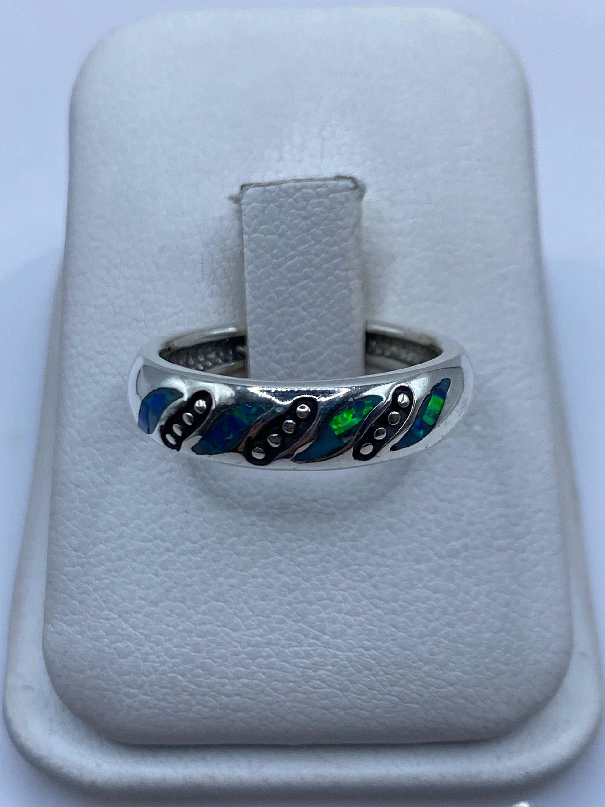 Anillo de plata con ópalo de fuego azul y verde en la mano de una mujer
