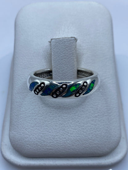 Anillo de plata con ópalo de fuego azul y verde en la mano de una mujer
