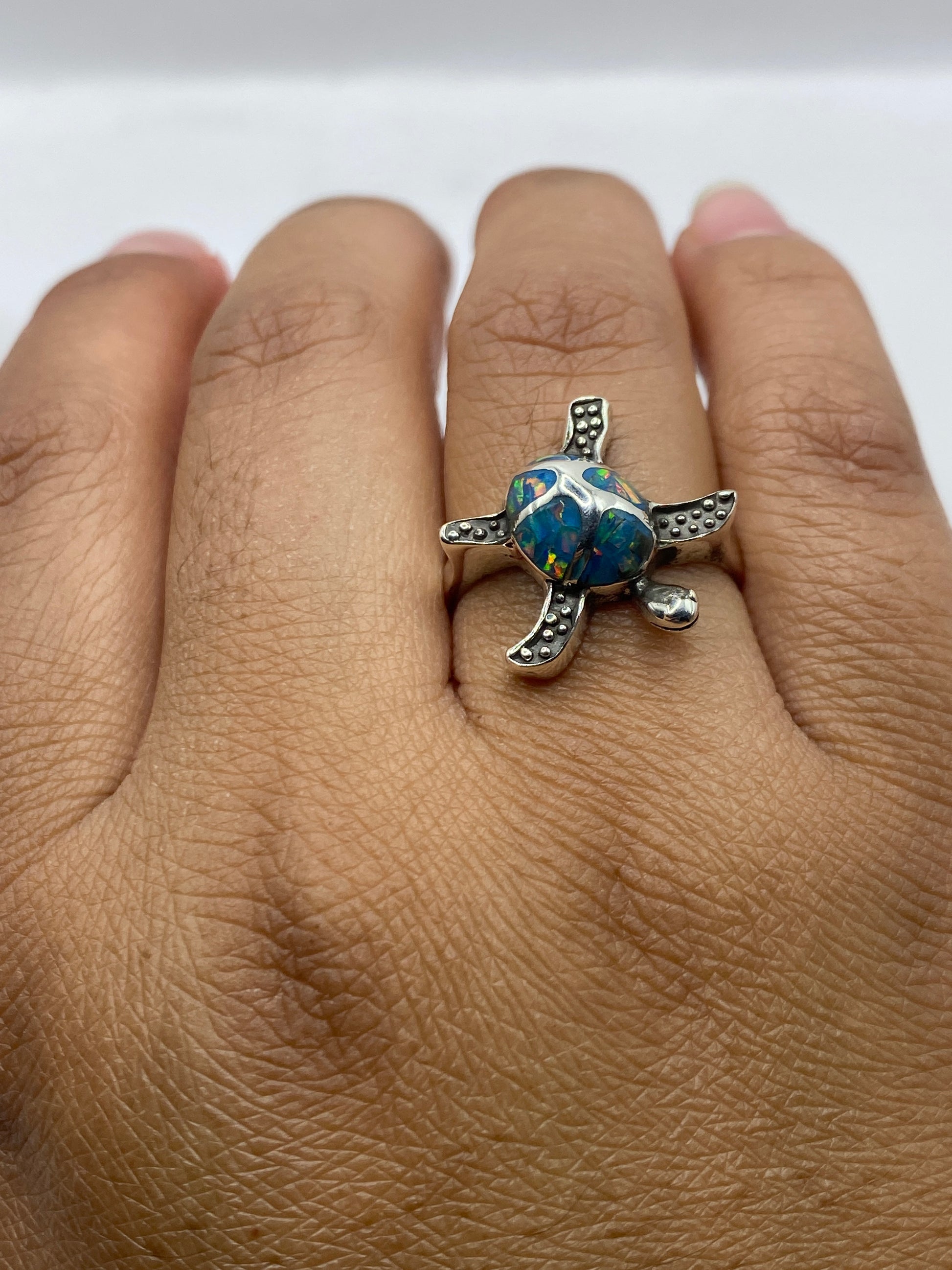 Anillo tortuga en dedo mostrando el juego de color del ópalo de fuego