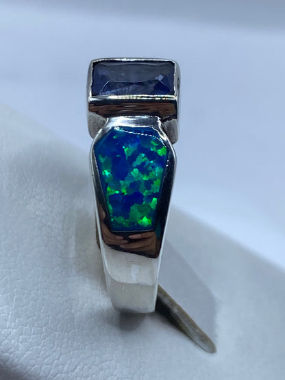 Anillo tripartito de plata en la mano, reflejando fuego cromático azul-verde