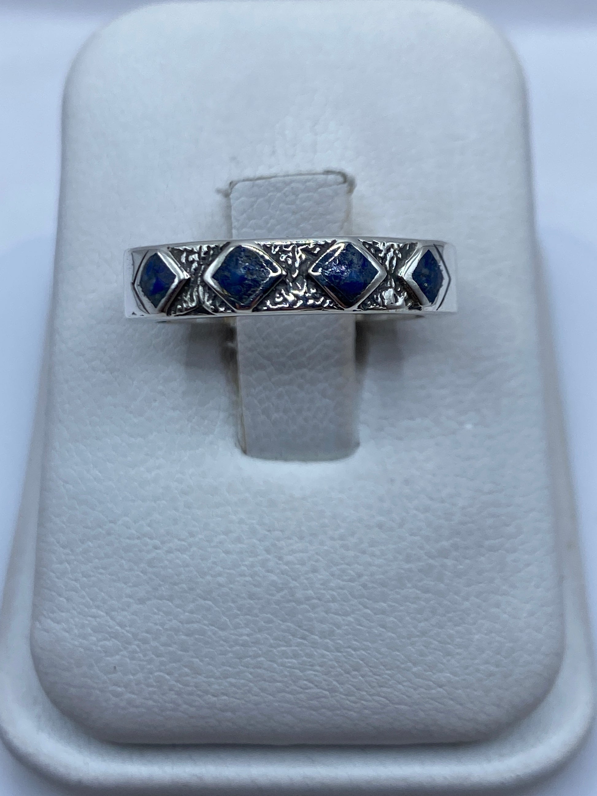 Anillo de plata con lapislázuli azul profundo y vetas doradas en la mano de una persona