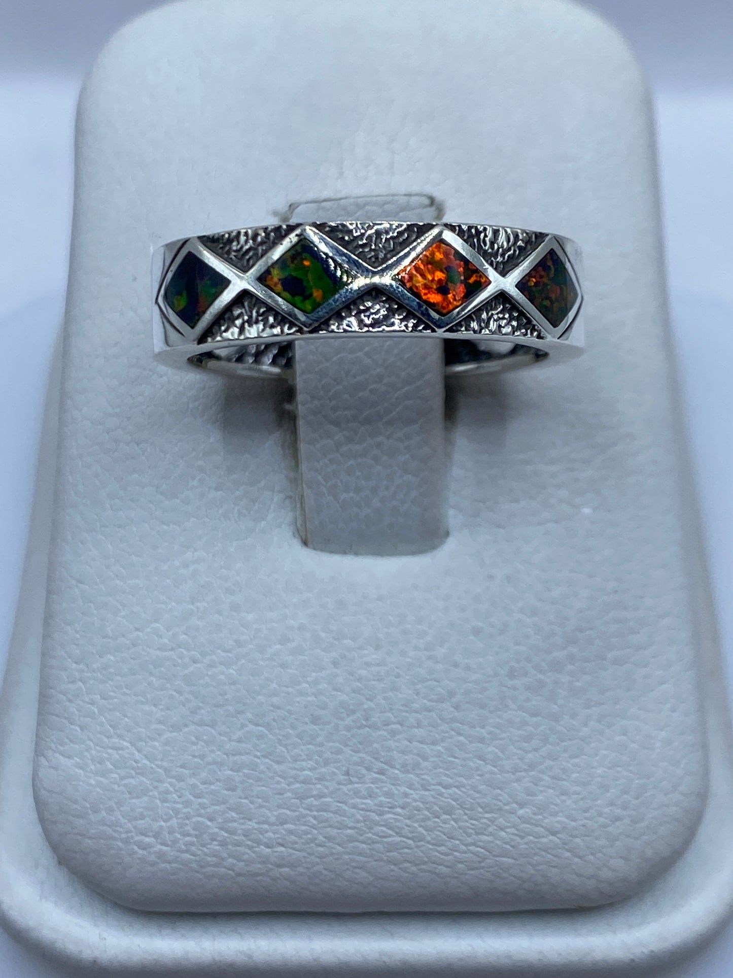 Anillo de plata con ópalo de fuego multicolor sobre soporte blanco