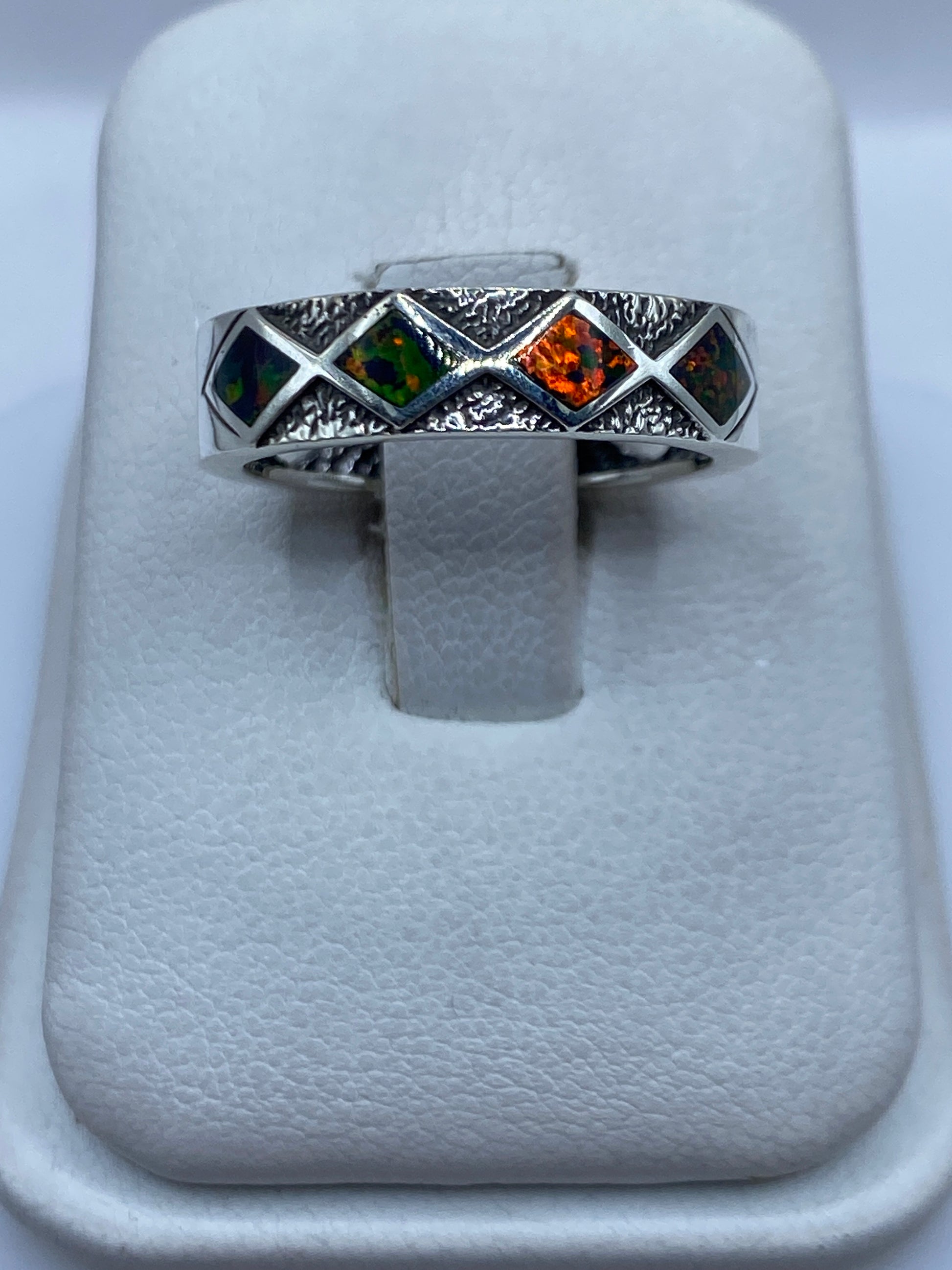 Anillo de plata con ópalo de fuego multicolor sobre soporte blanco