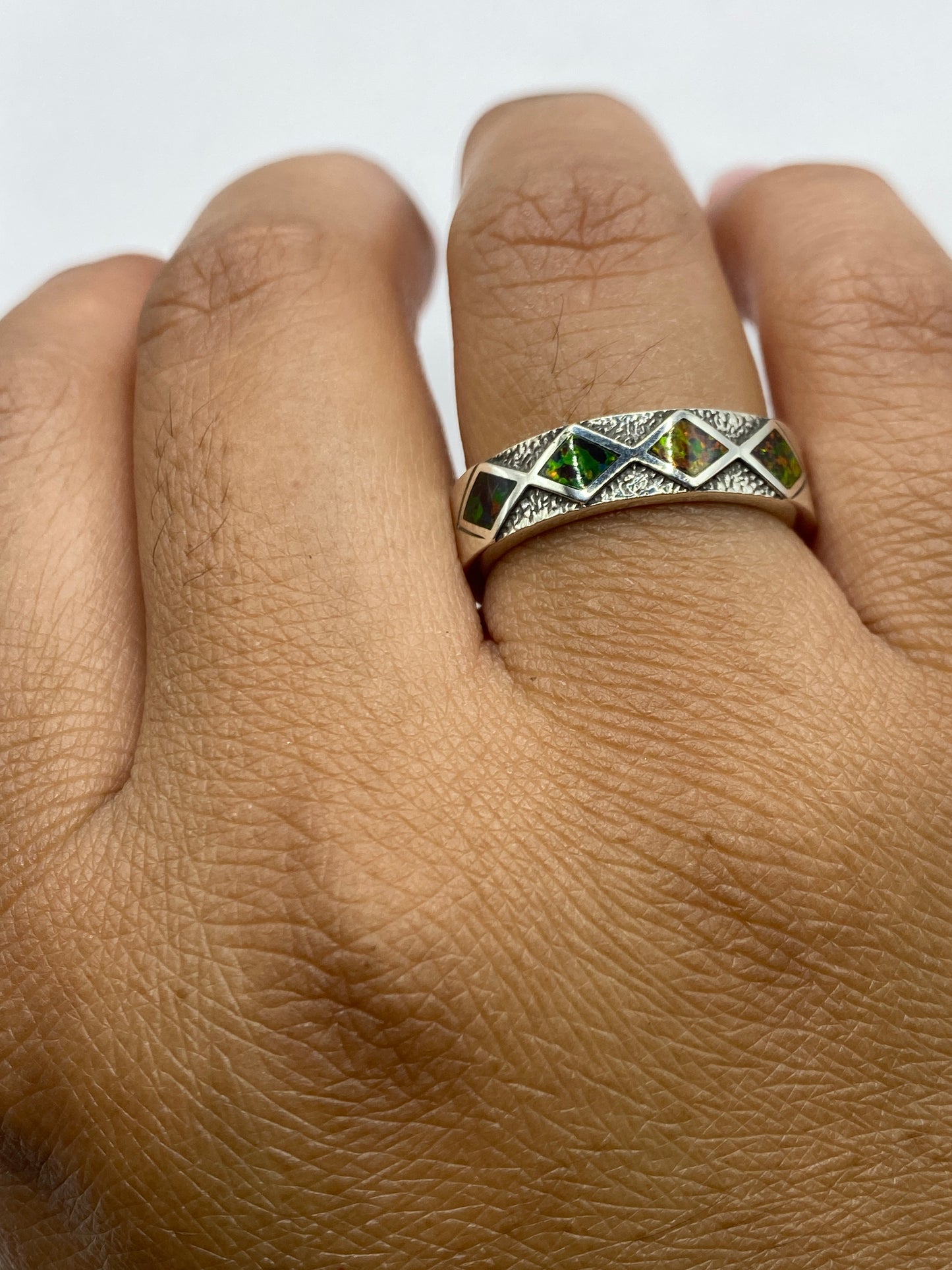 Anillo llevado en dedo, ópalo brillante bajo luz natural