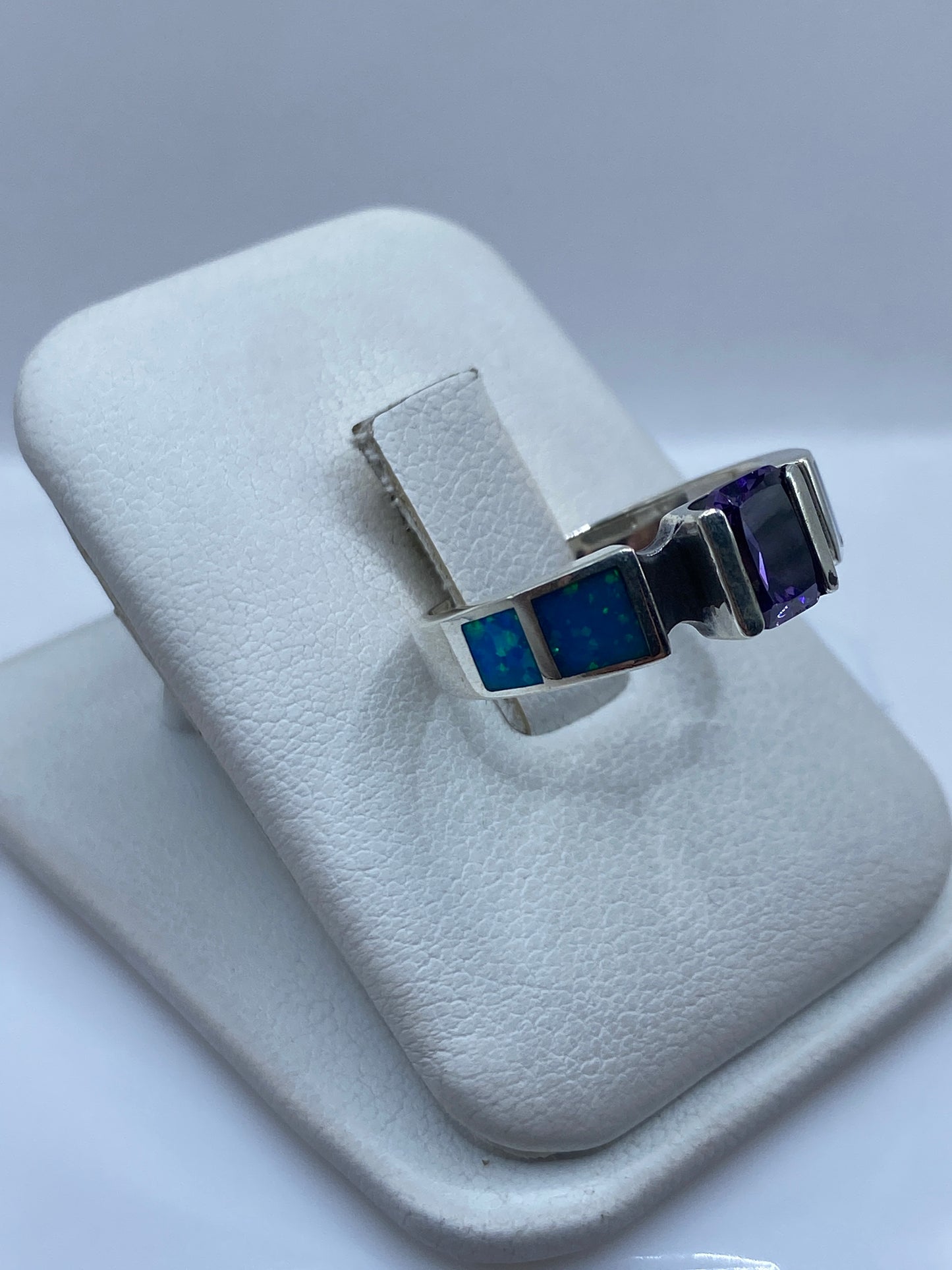 Vista frontal del anillo mostrando el ópalo azul con destellos cromáticos y bandas laterales en plata