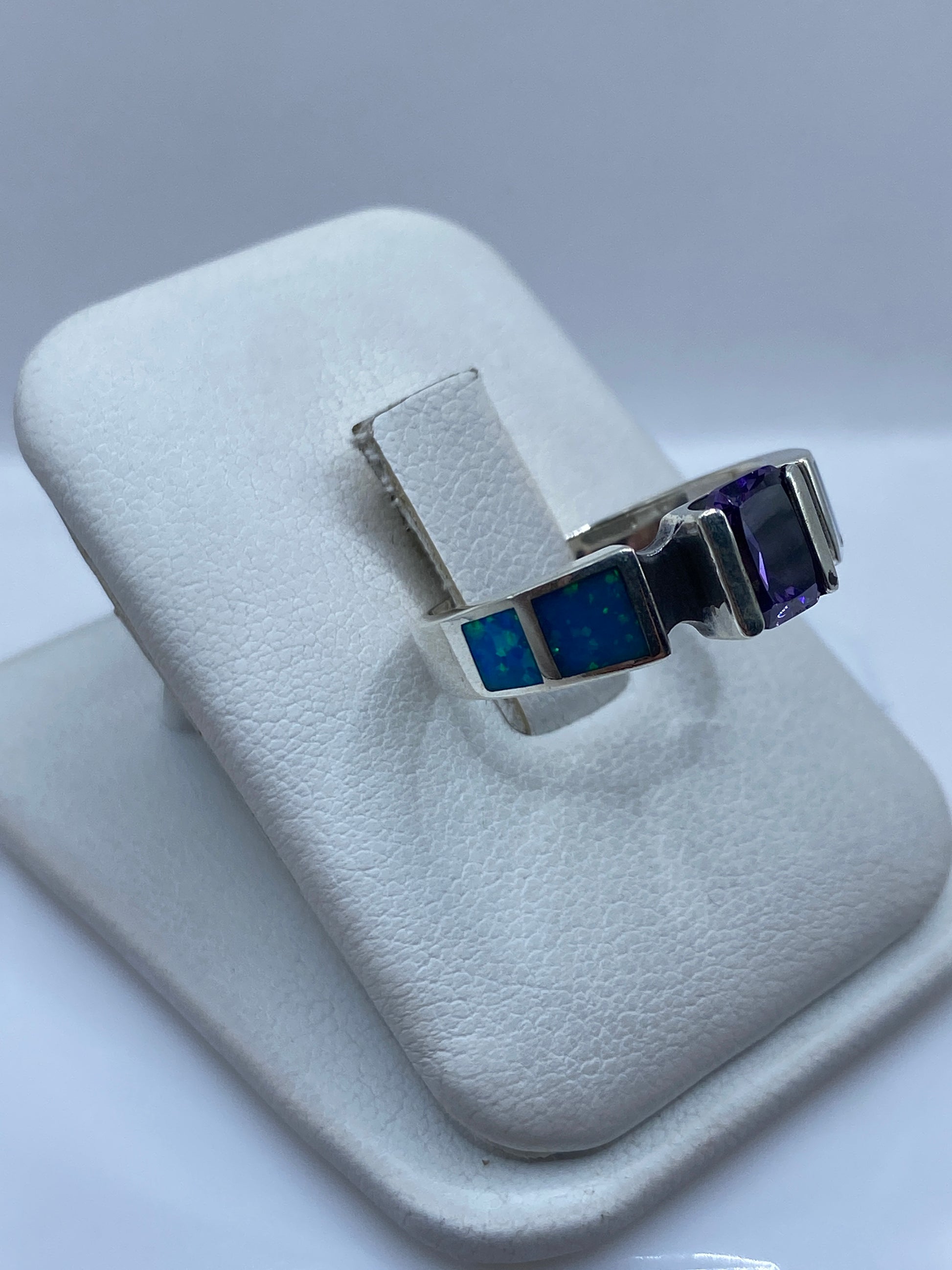 Vista frontal del anillo mostrando el ópalo azul con destellos cromáticos y bandas laterales en plata