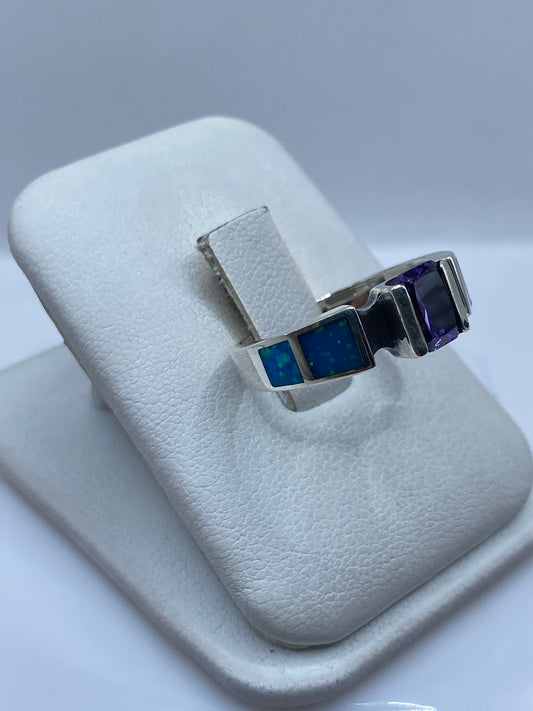 Vista frontal del anillo mostrando el ópalo azul con destellos cromáticos y bandas laterales en plata