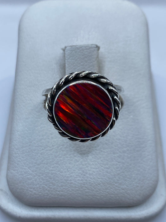 Anillo de plata con ópalo de fuego multicolor en banda torneada sobre fondo blanco
