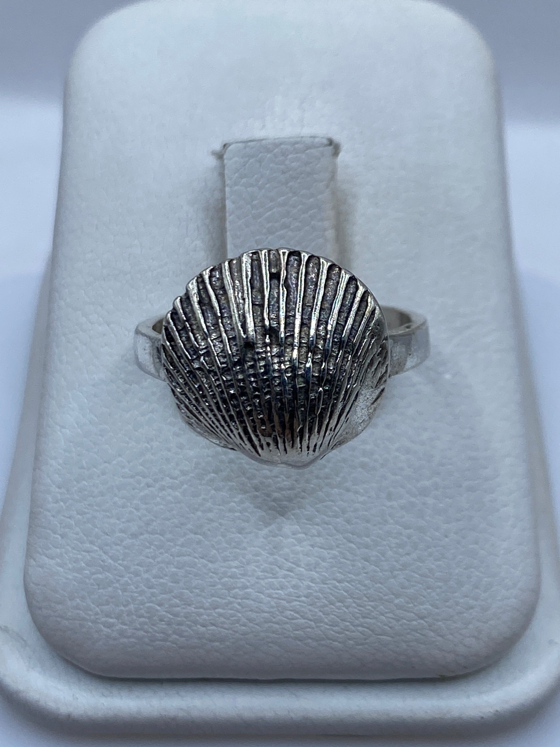 Anillo de plata con diseño de concha marina en relieve sobre la mano