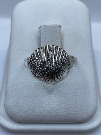 Anillo de plata con diseño de concha marina en relieve sobre la mano