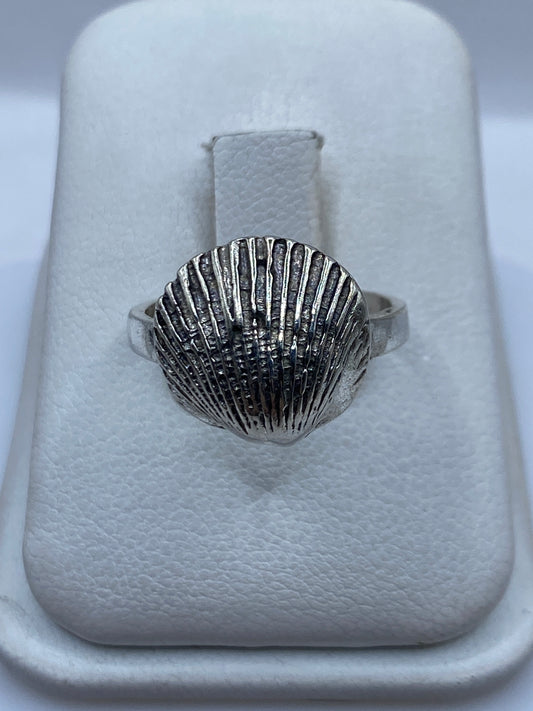Anillo de plata con diseño de concha marina en relieve sobre la mano