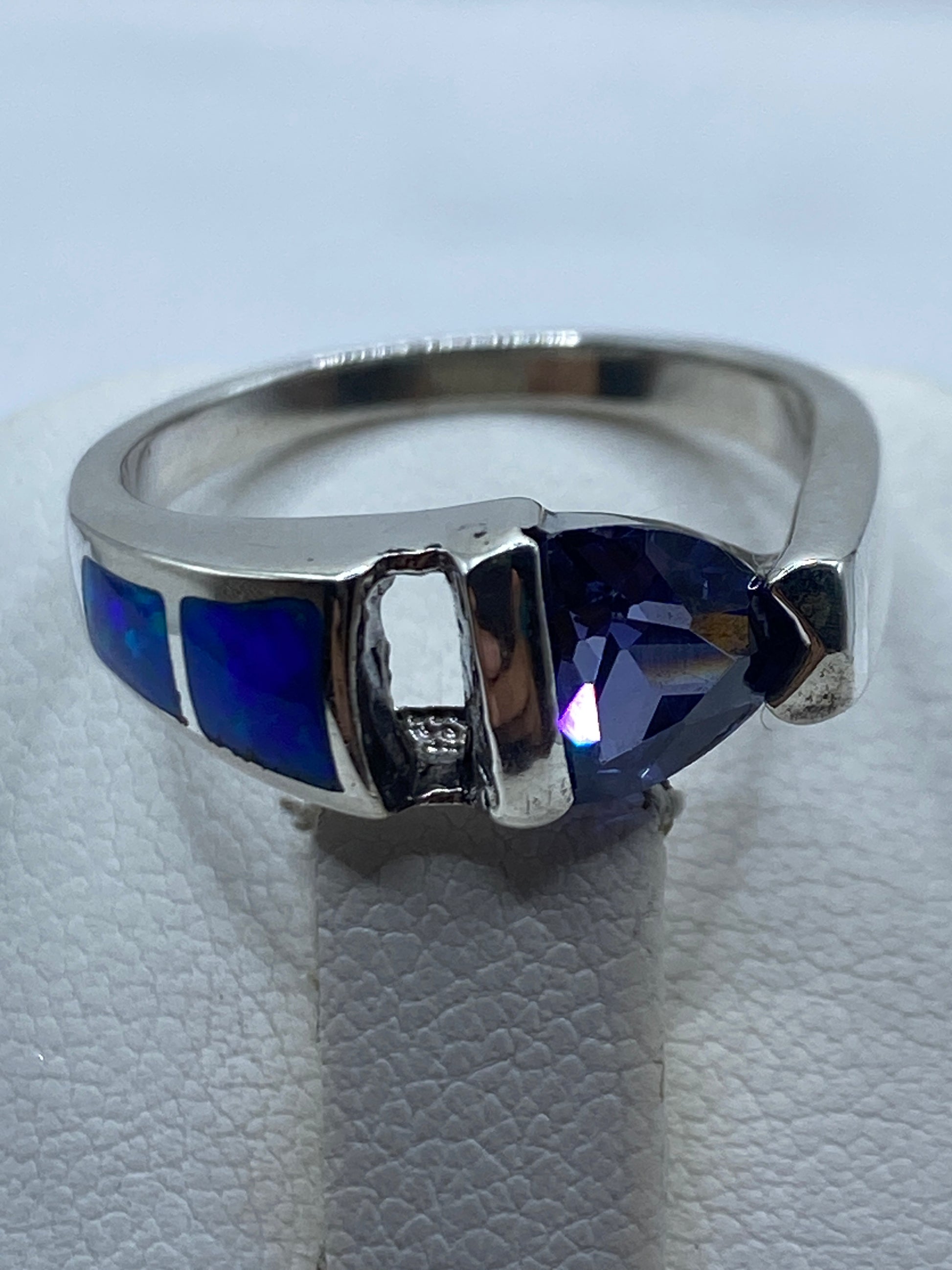 Anillo de plata con piedra de ópalo de fuego en dedo de mujer mostrando reflejos azules