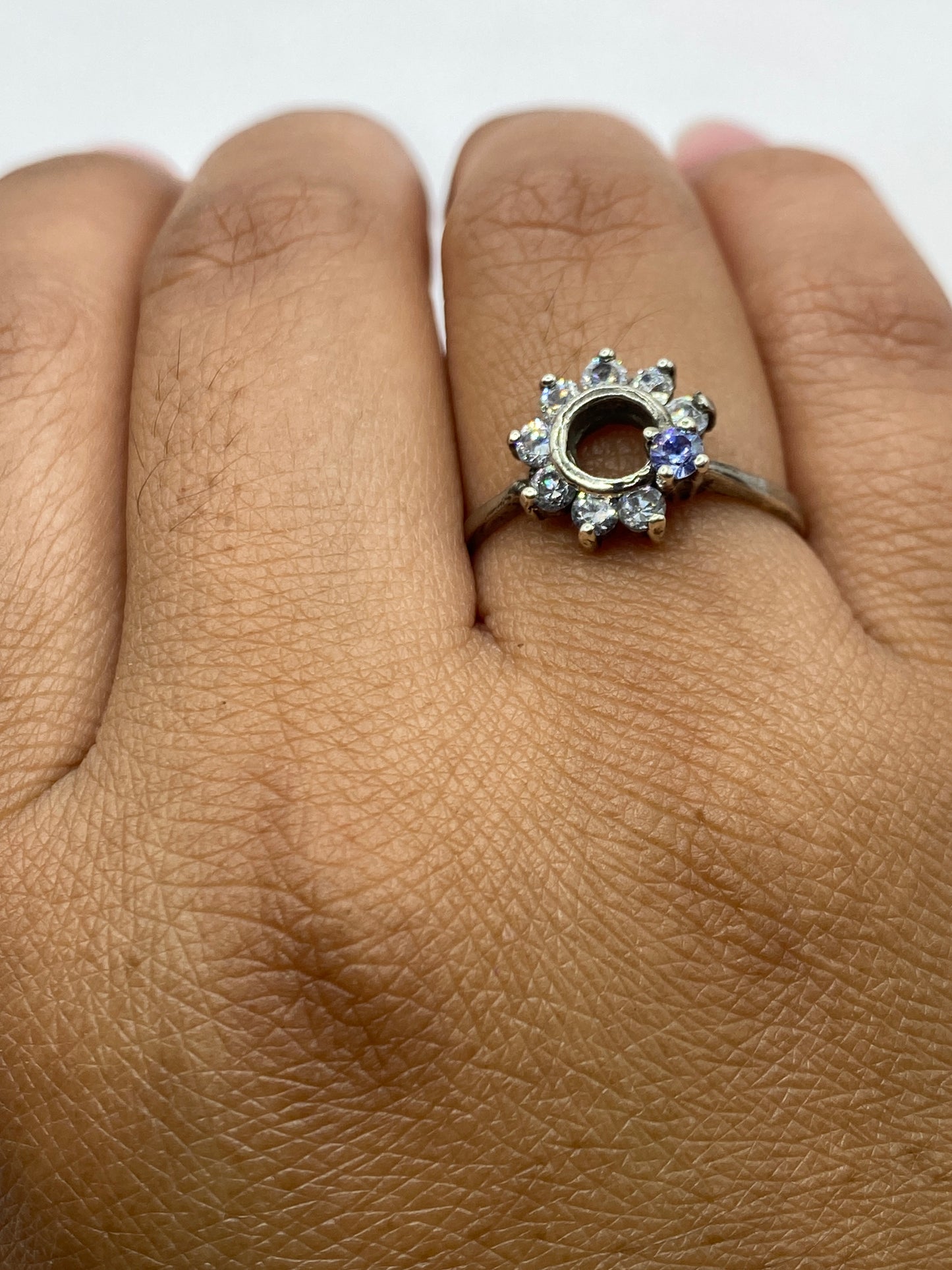 Anillo de plata solitario en mano de mujer, luz natural iluminando el brillo de la piedra