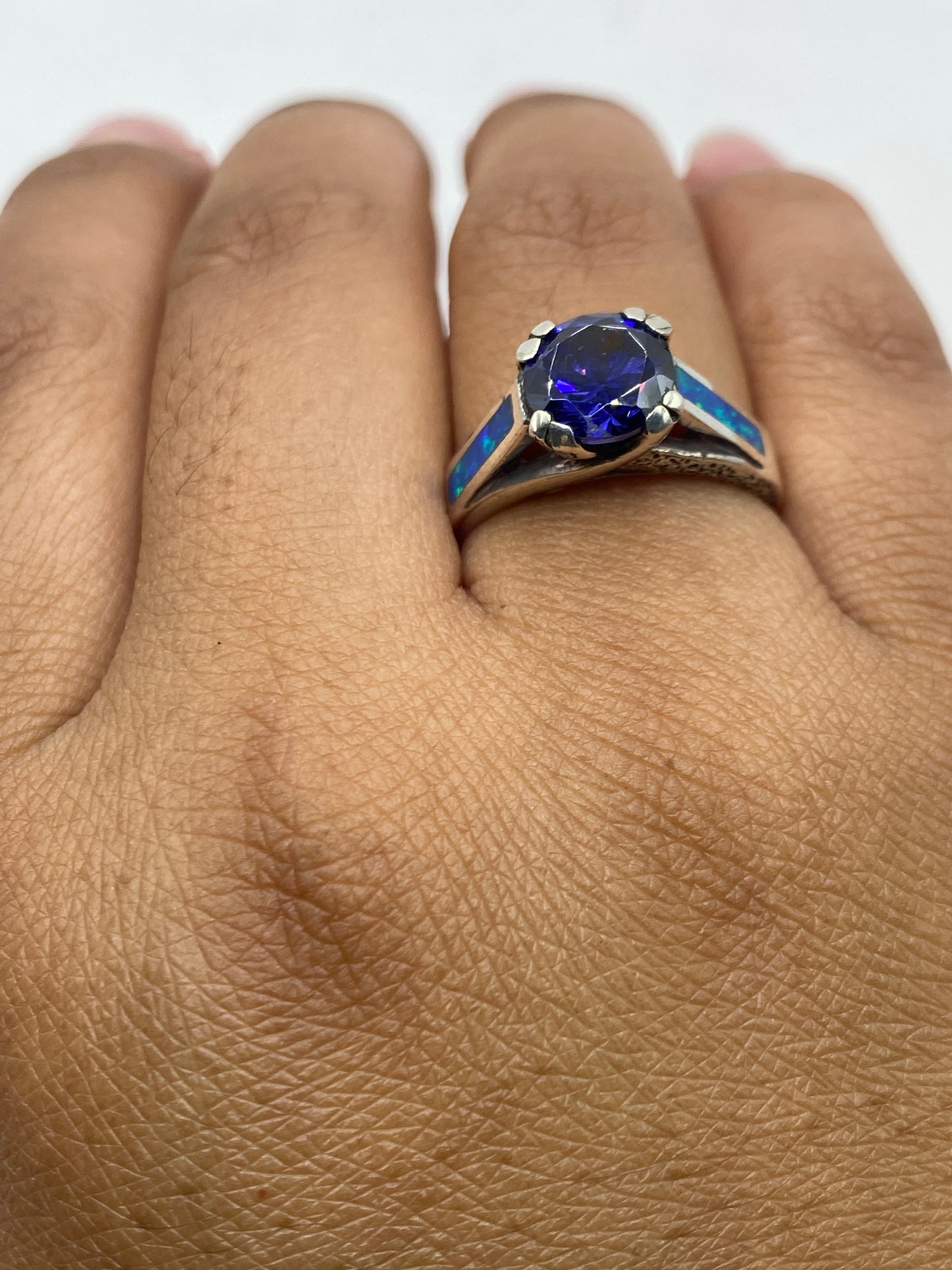 Anillo de ópalo de fuego azul con sello 950 visible, colocado en dedo mostrando tamaño real