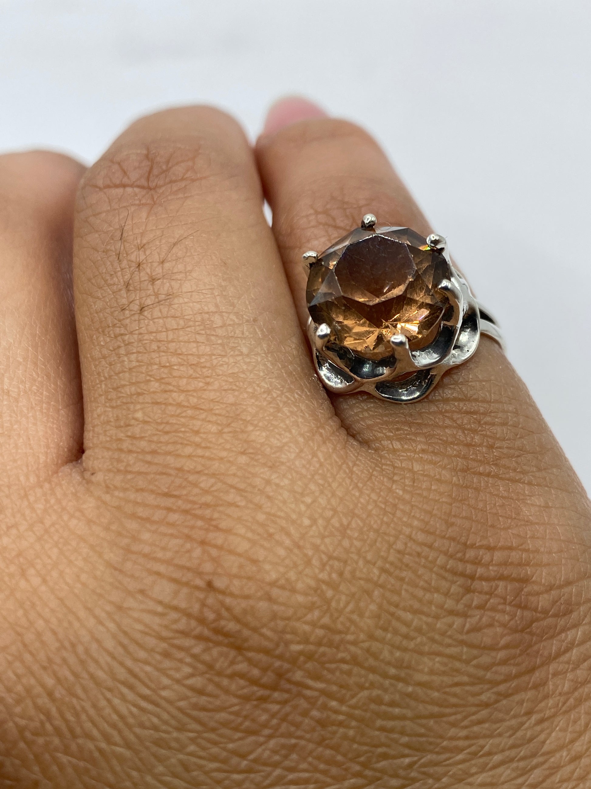 Anillo puesto en dedo, con luz natural resaltando el tono ámbar de la circonia