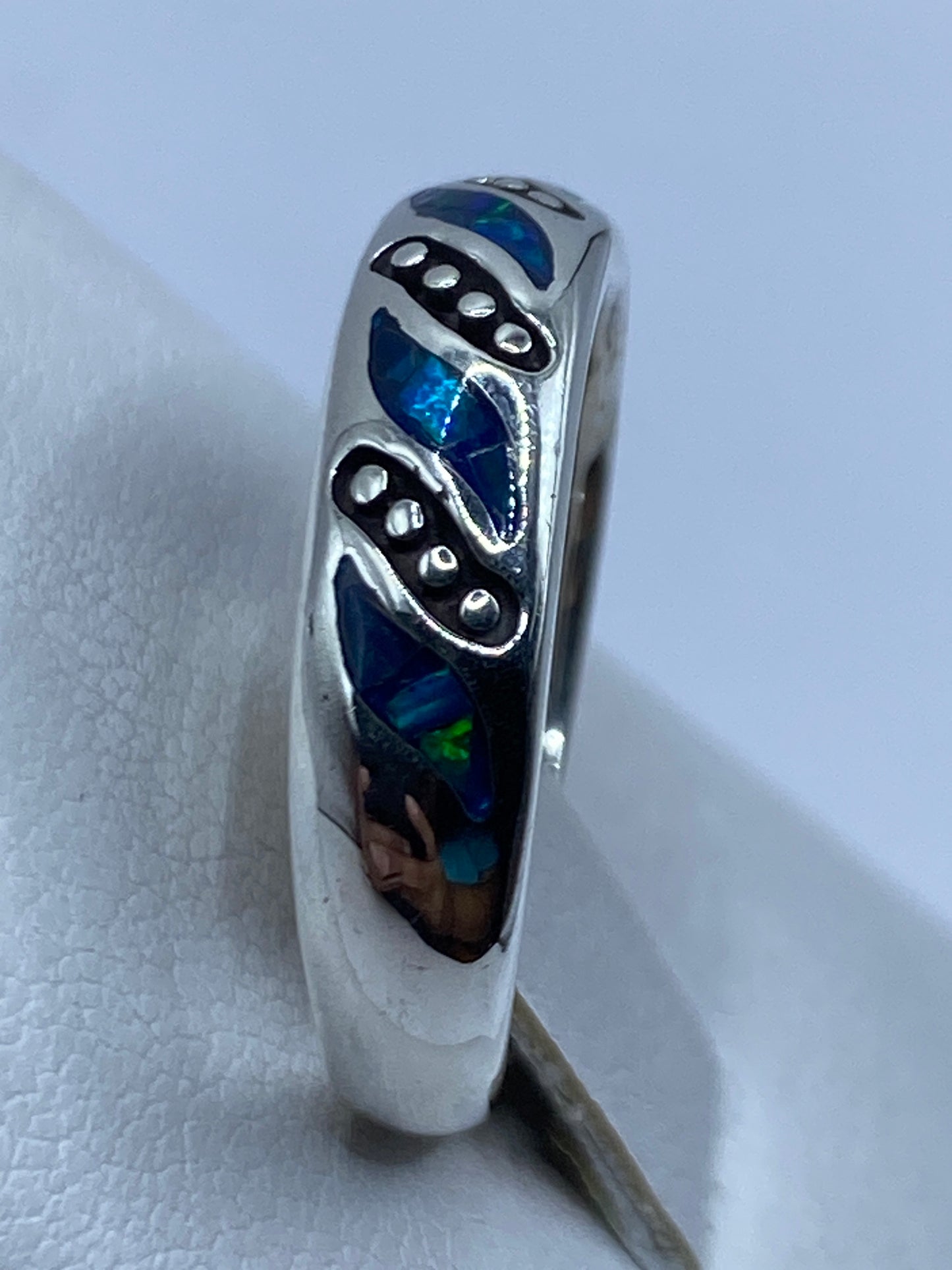 Detalle del ópalo azul en la mano, iluminado mostrando el fuego y iridiscencia natural