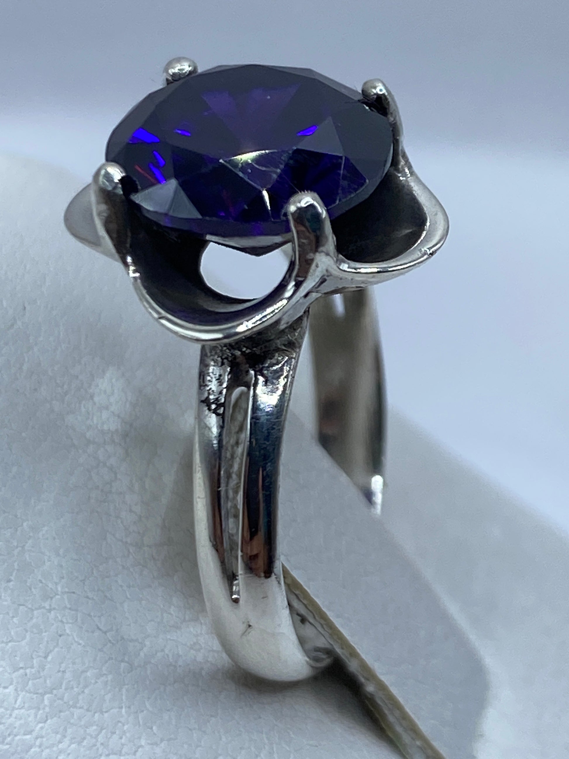 Anillo solitario de circonia morada en la mano, brillando con fuego tipo amatista