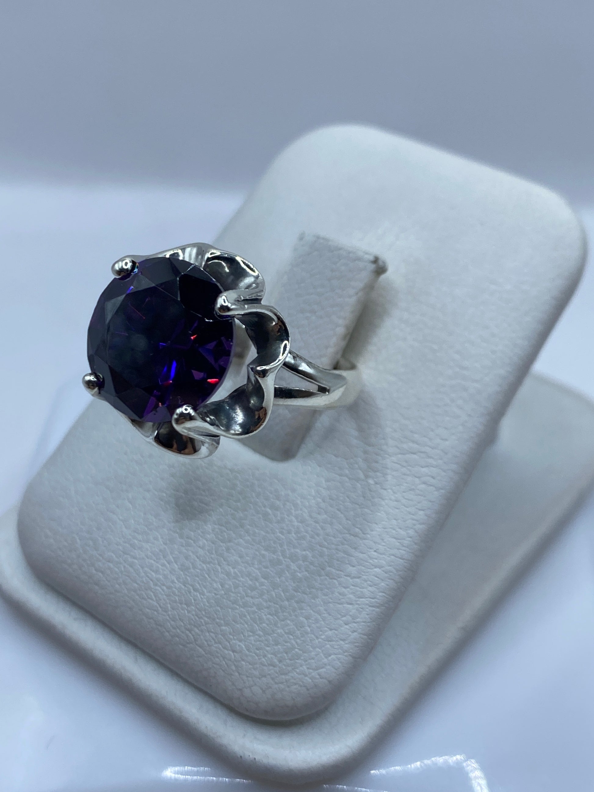 Vista lateral del anillo de plata .925 con engaste decorativo de corolas y circonia morada