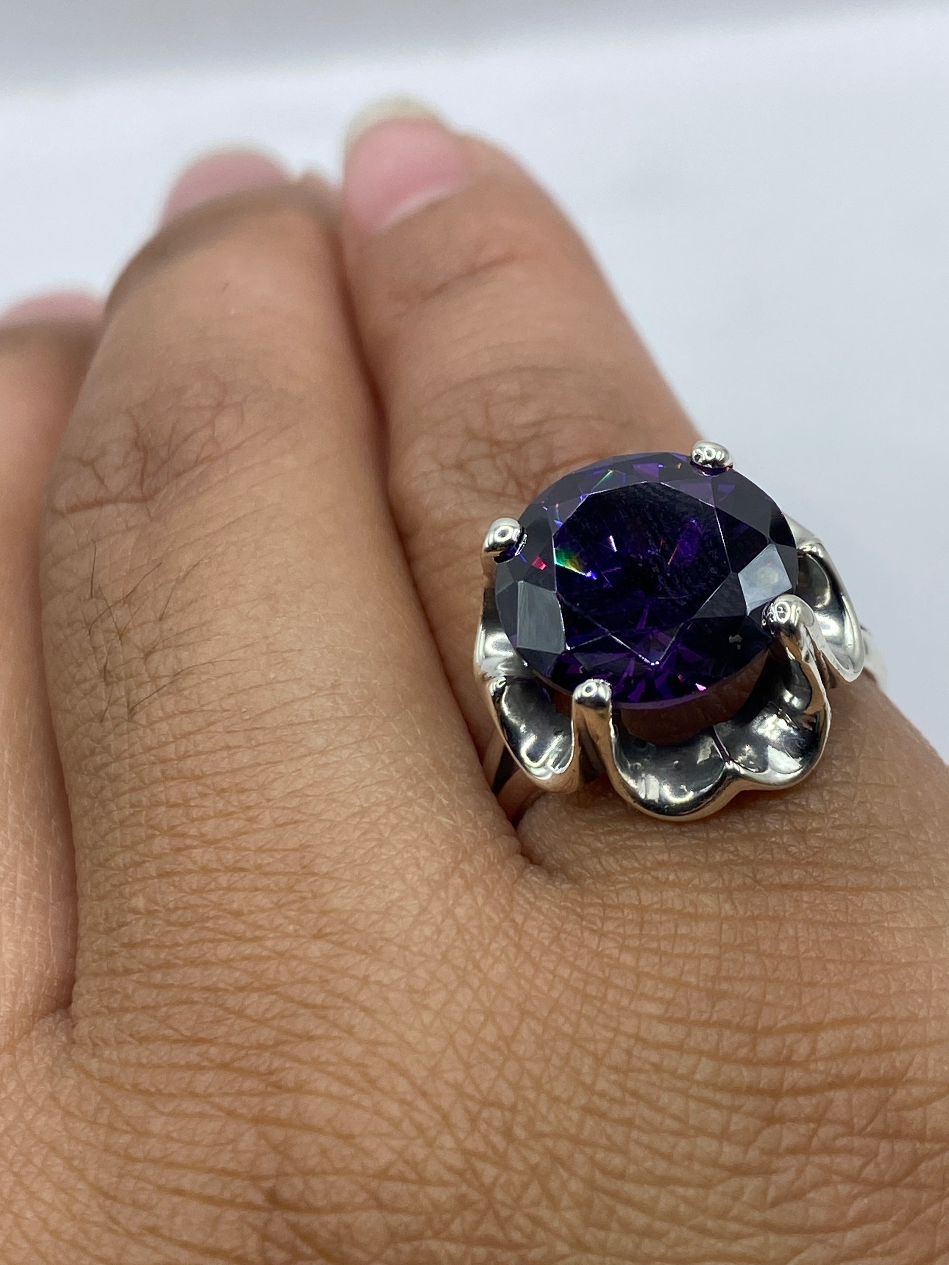 Anillo en la mano mostrando cómo luce la circonia morada contra la piel, con el sello .925