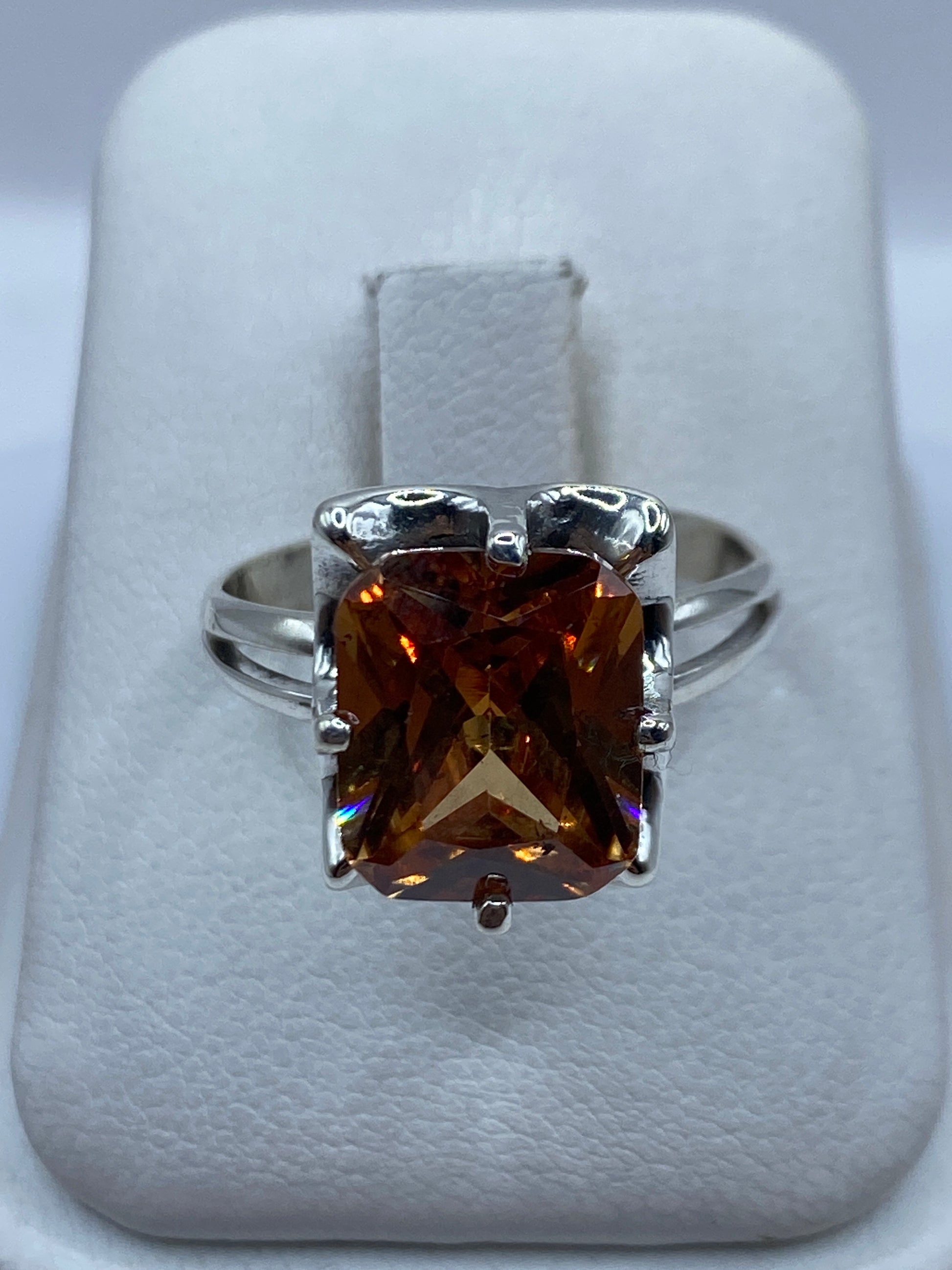 Anillo de plata solitario con circonia ámbar en la mano de una mujer