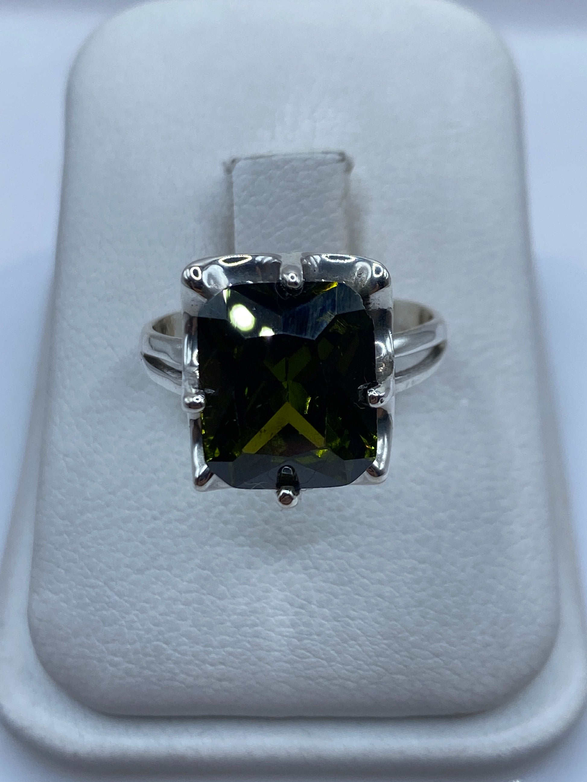 Anillo solitario de plata con circonia verde olivo facetada en dedo de mujer